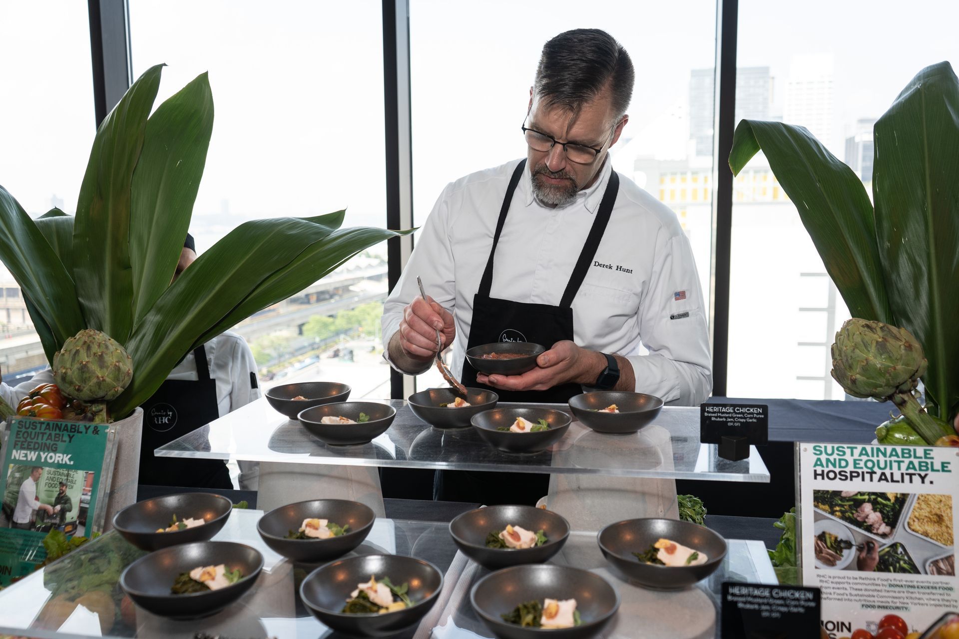 A chef is preparing food on a table in front of a window.