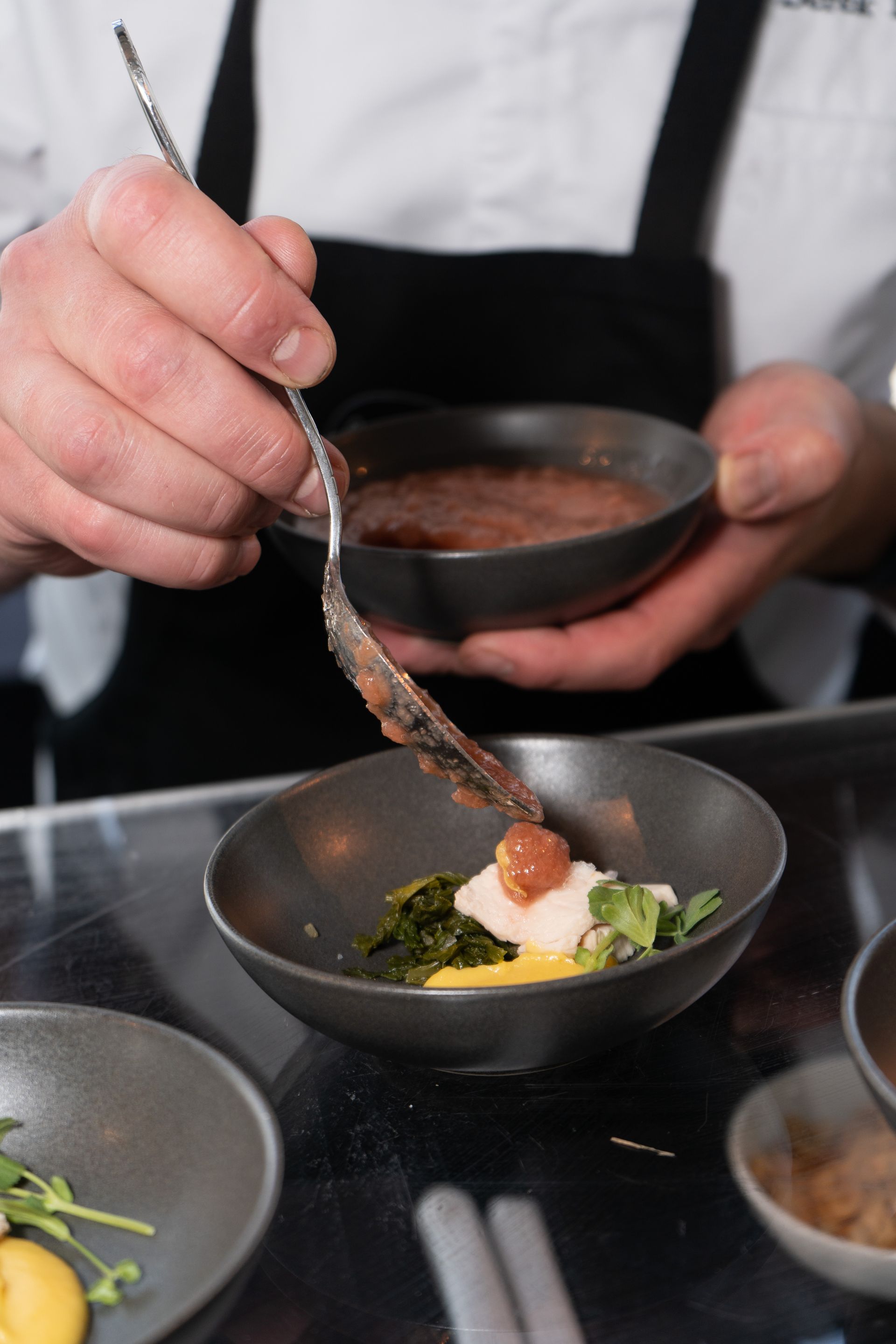 A chef is preparing food in a bowl with a spoon.