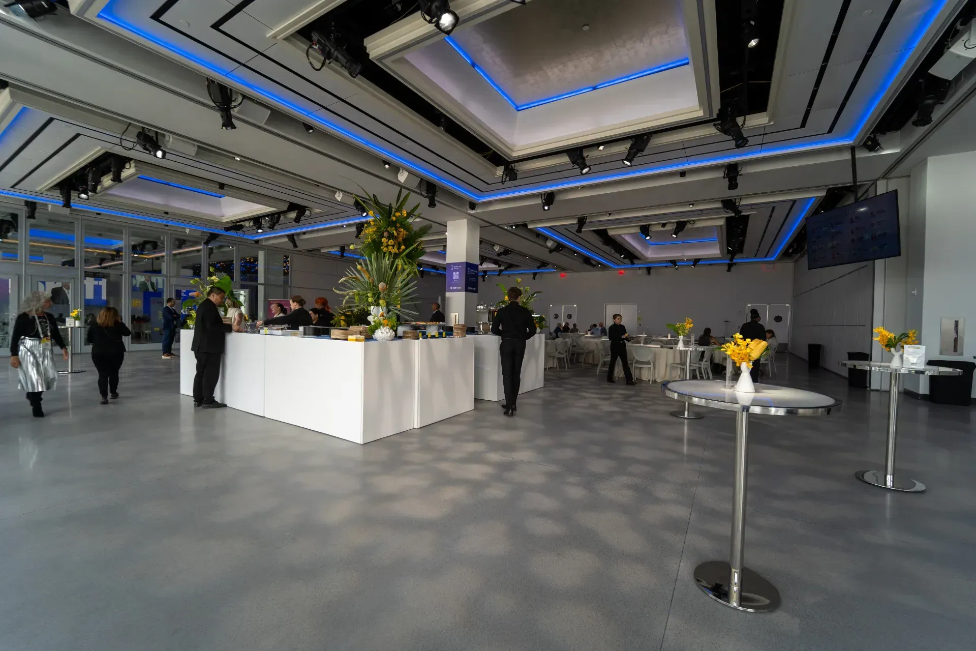 A large room with tables and people standing in it.