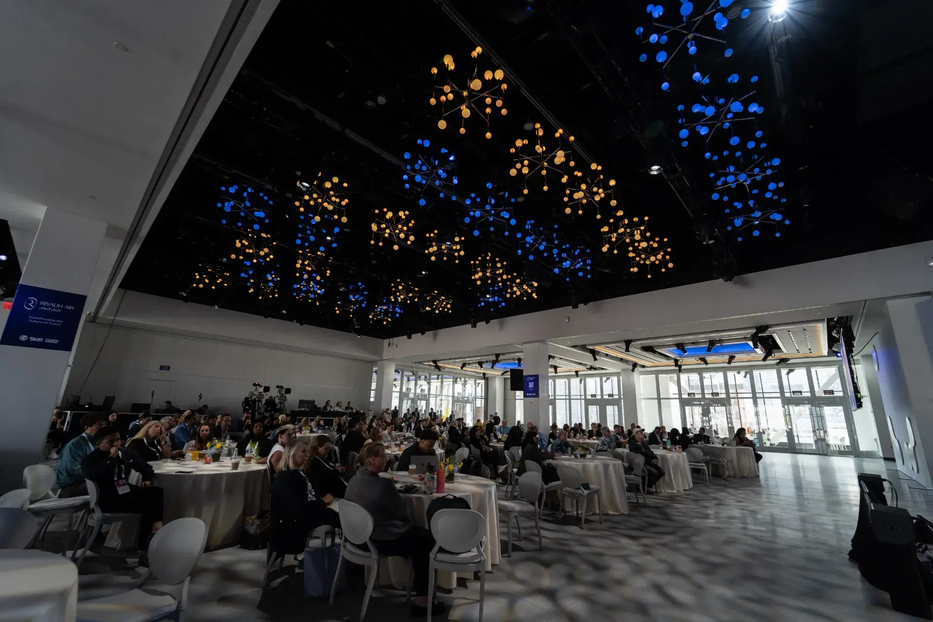 A group of people are sitting at tables in a large room.