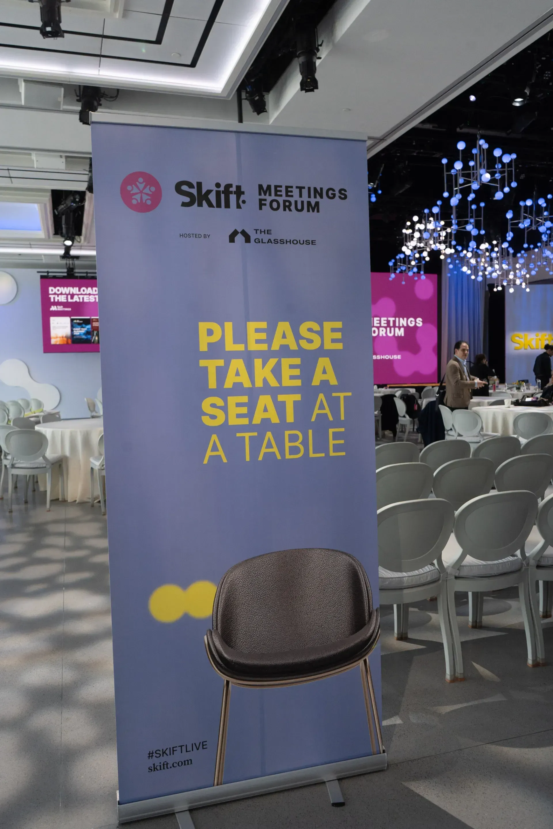 A sign that says please take a seat at a table