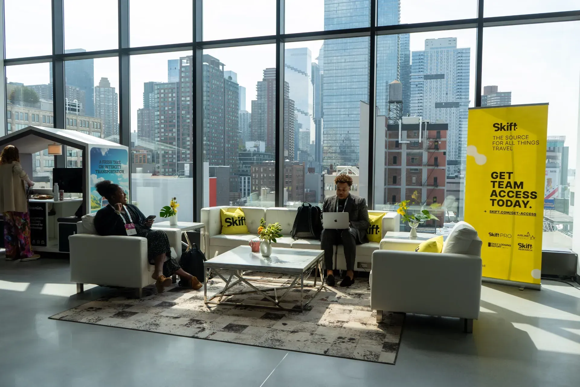 A woman is sitting on a couch in a living room with a laptop.