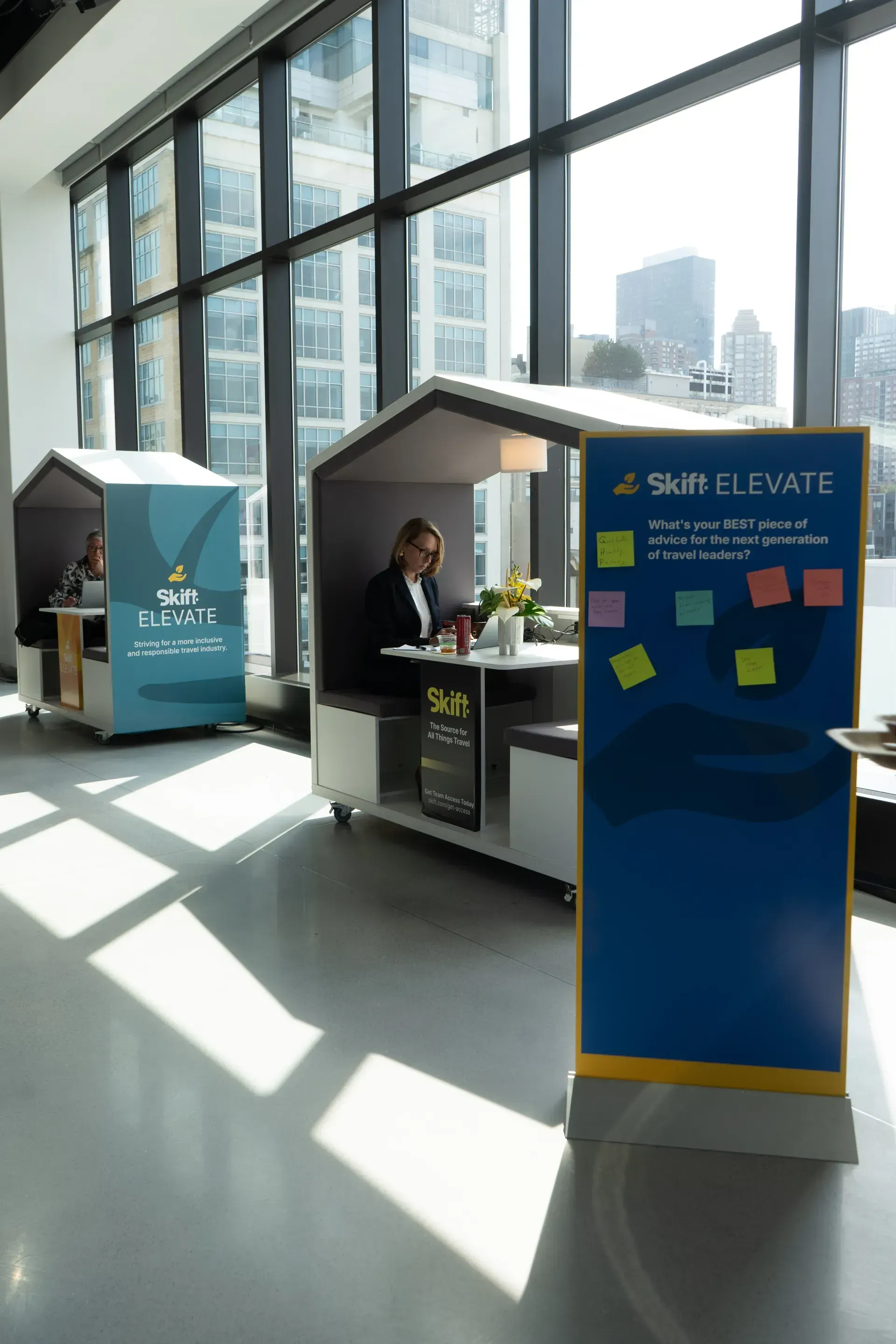A man is sitting at a table in a booth in front of a large window.