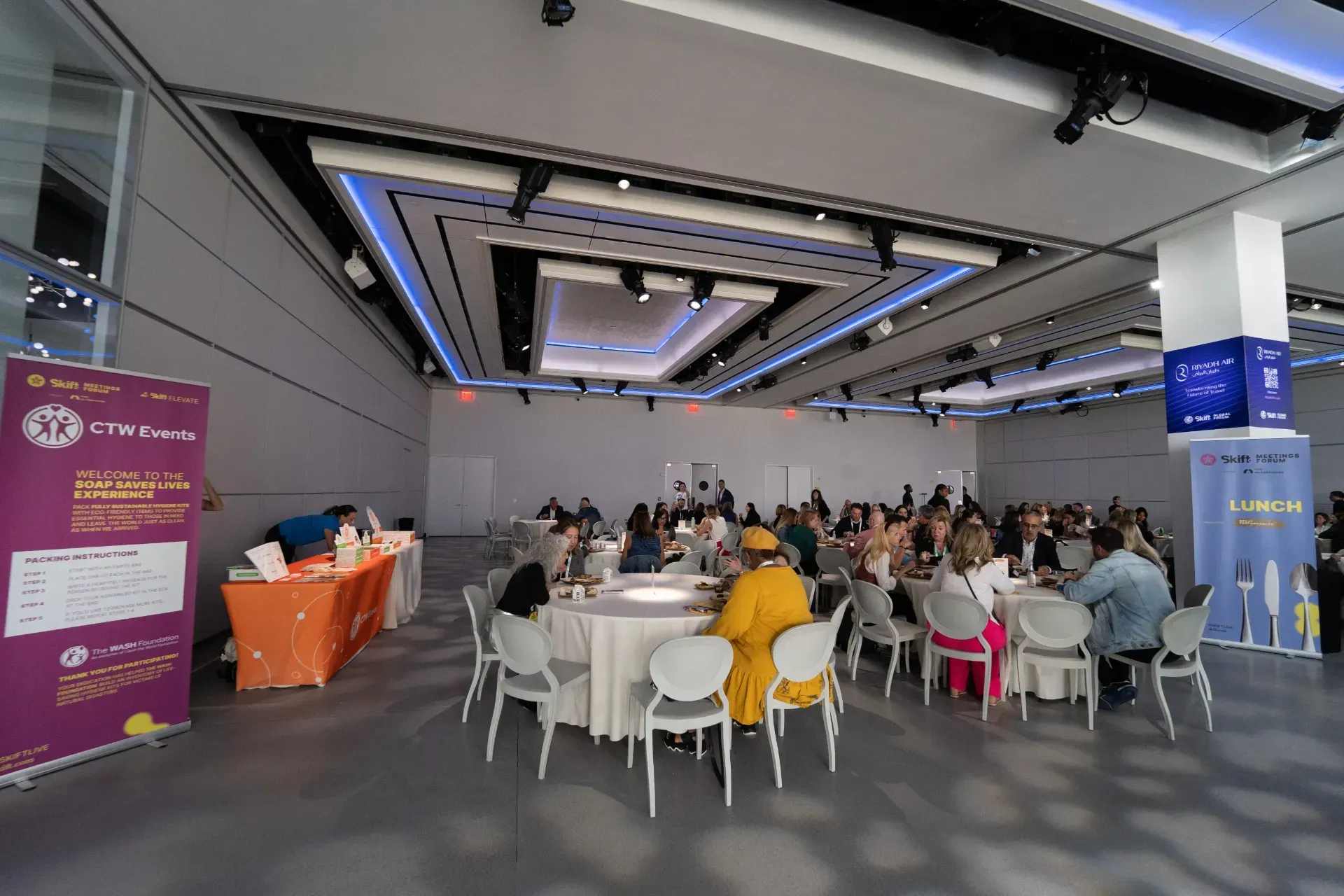 A large room filled with people sitting at tables and chairs.