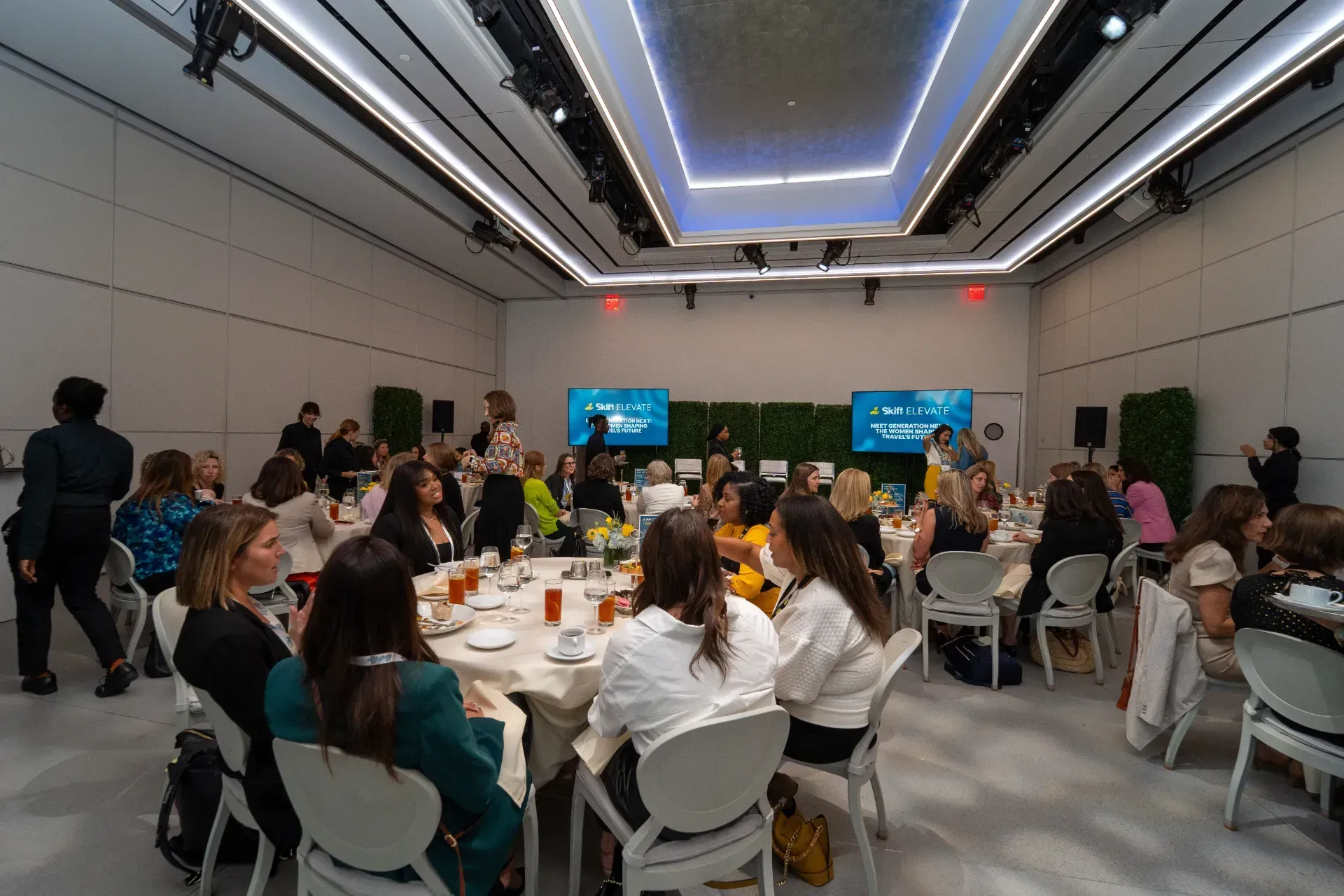 A group of people are sitting at tables in a large room.