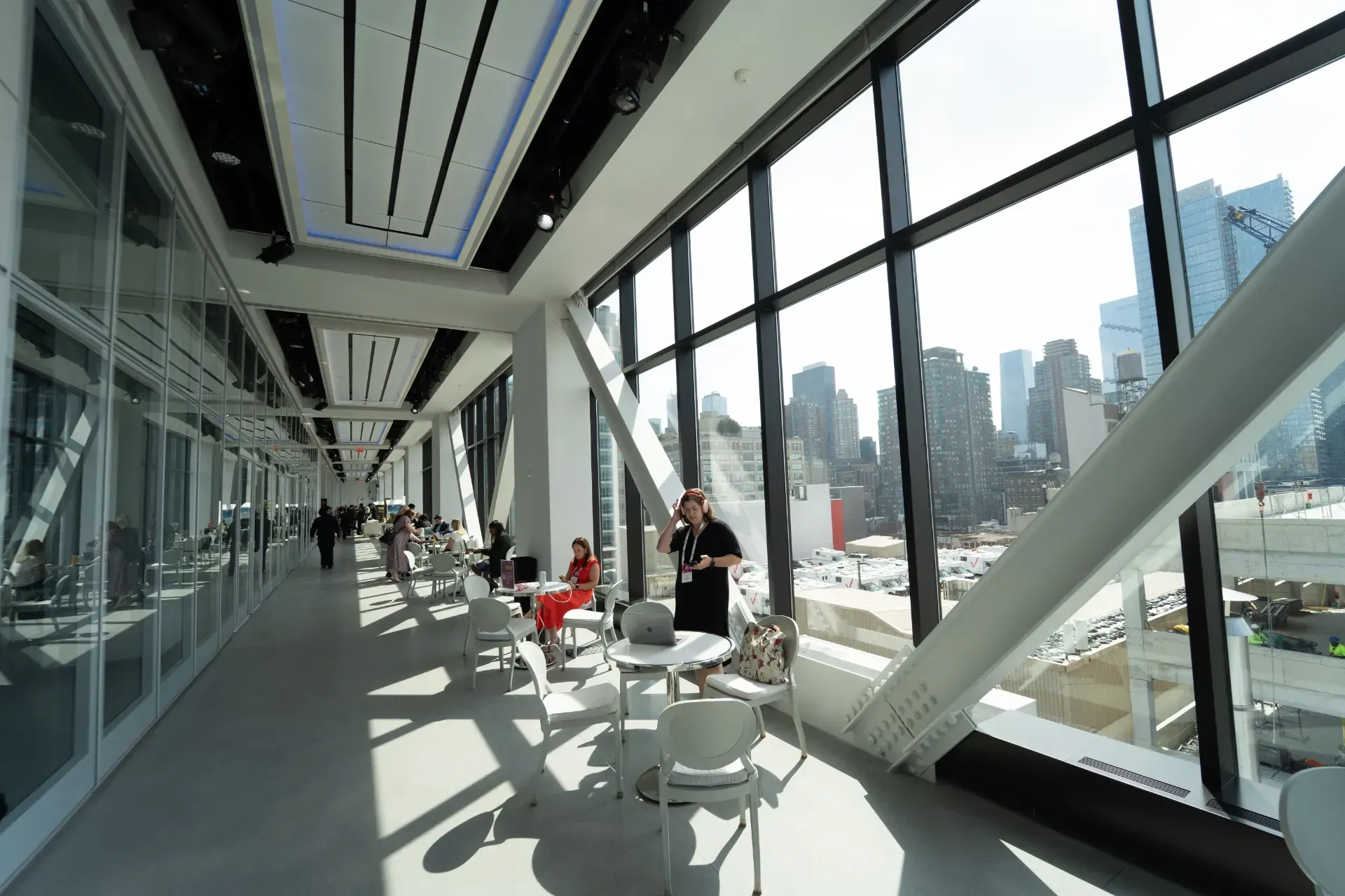 A long hallway with tables and chairs and a view of the city