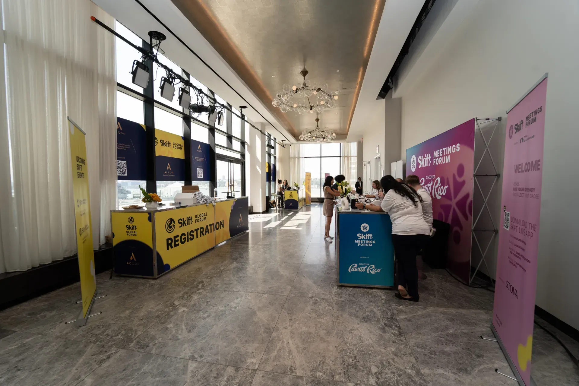 A long hallway with tables and chairs and a view of the city