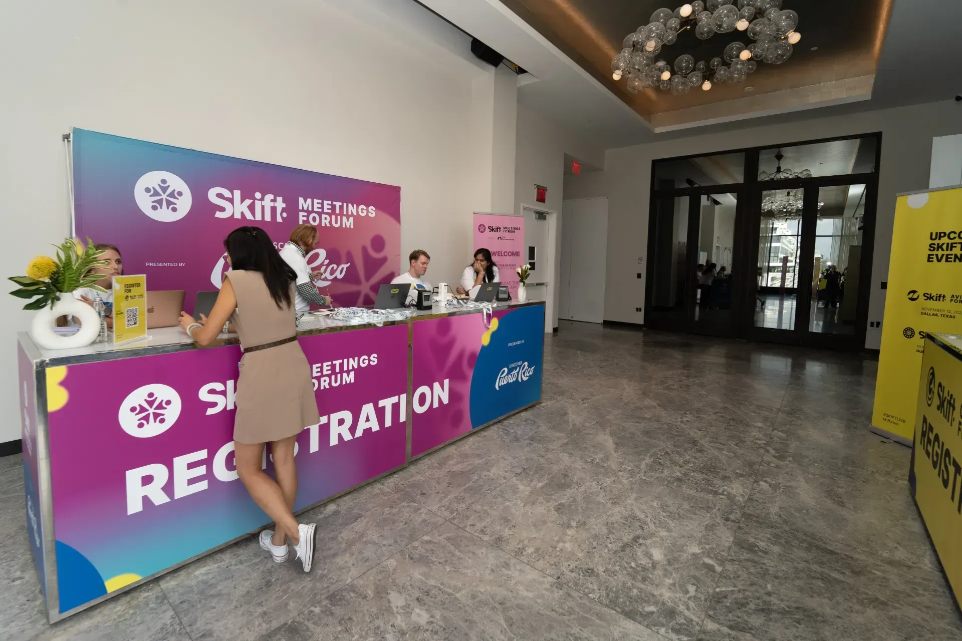 A woman is standing in front of a registration desk in a lobby.