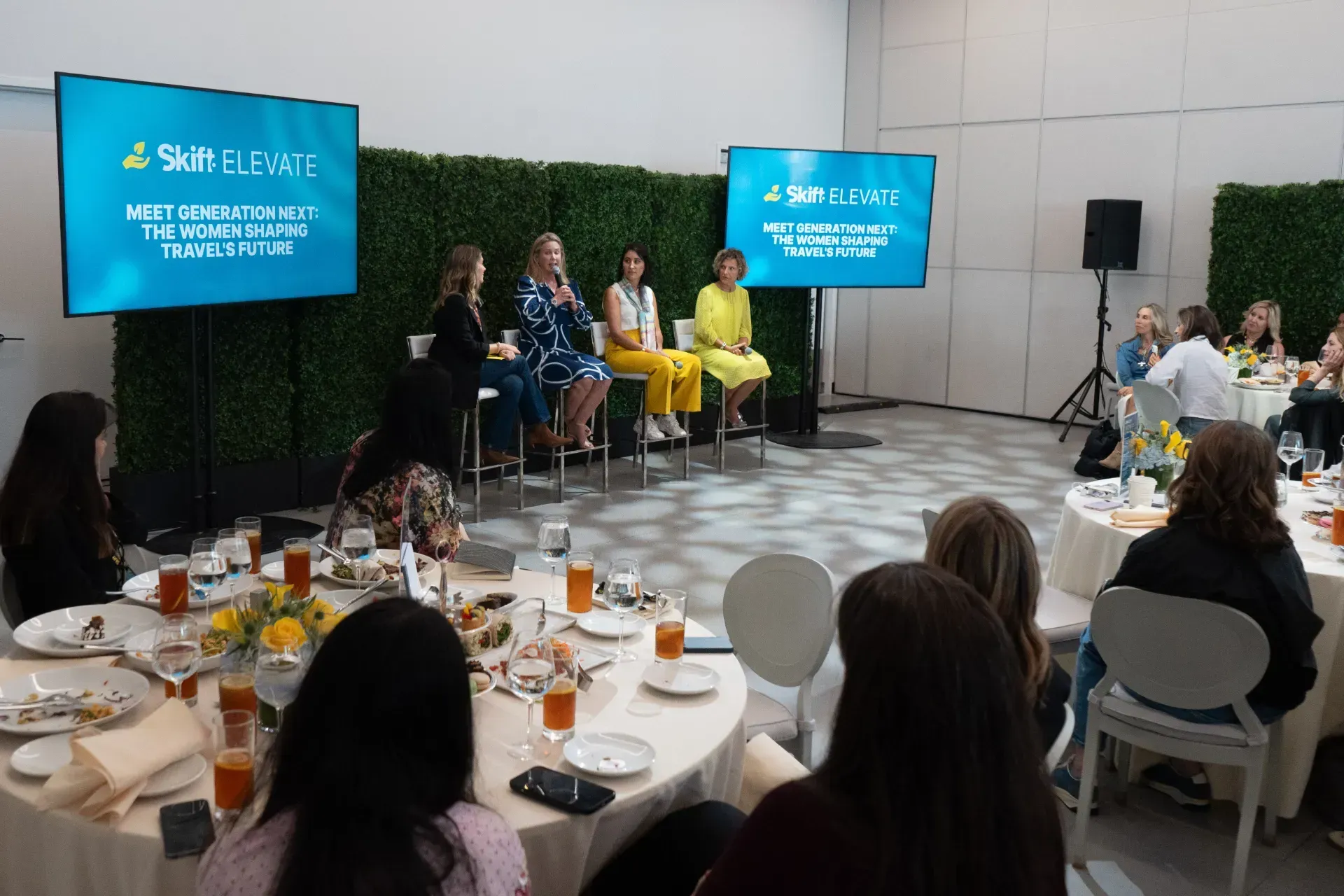 A group of people are sitting at tables watching a presentation.