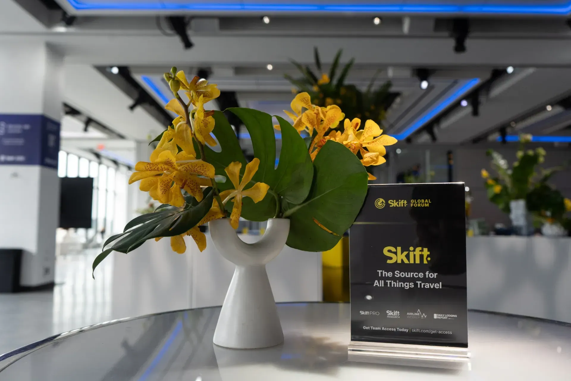 A vase of yellow flowers sits on a table next to a sign that says shift