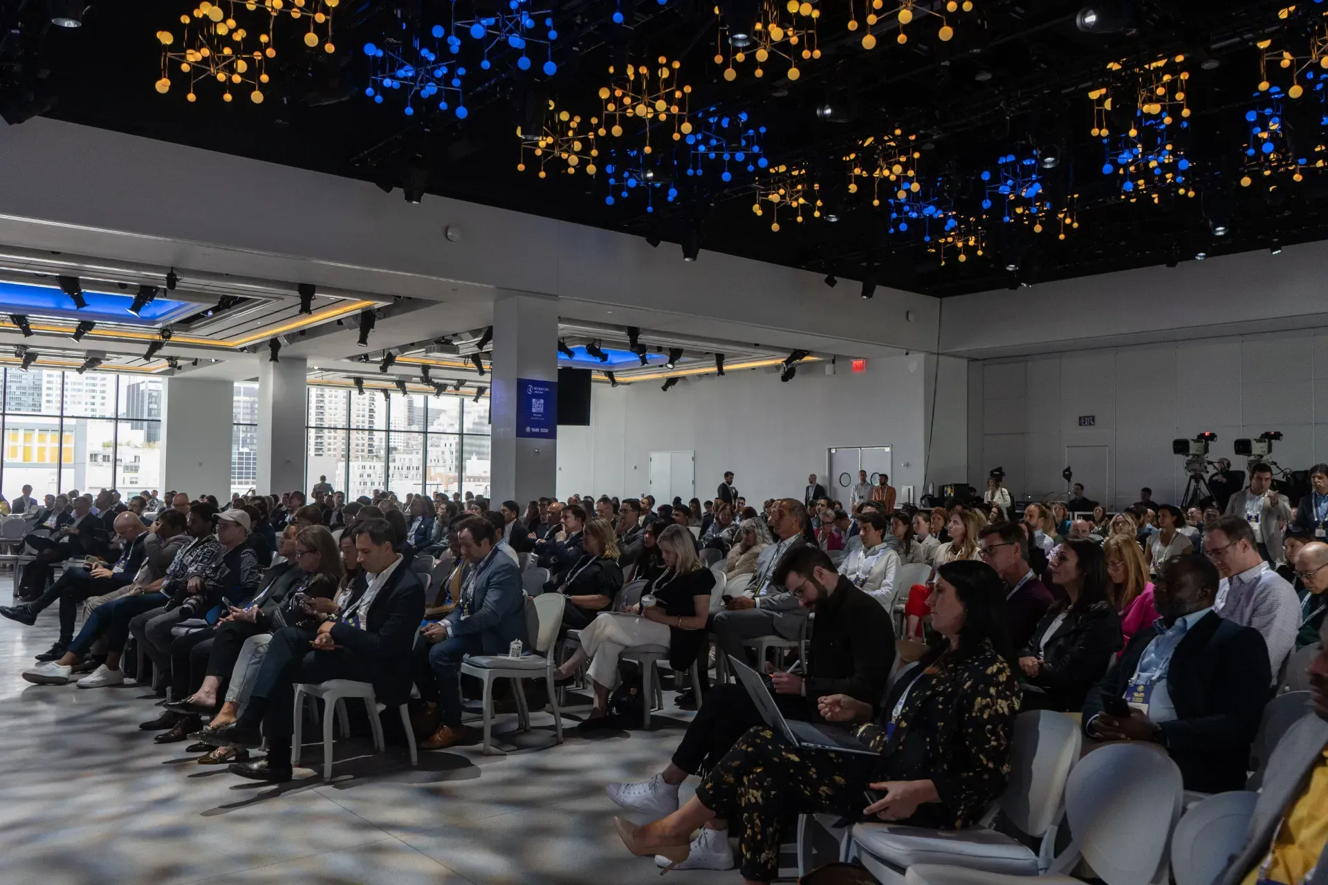 A large group of people are sitting in chairs in a large room.