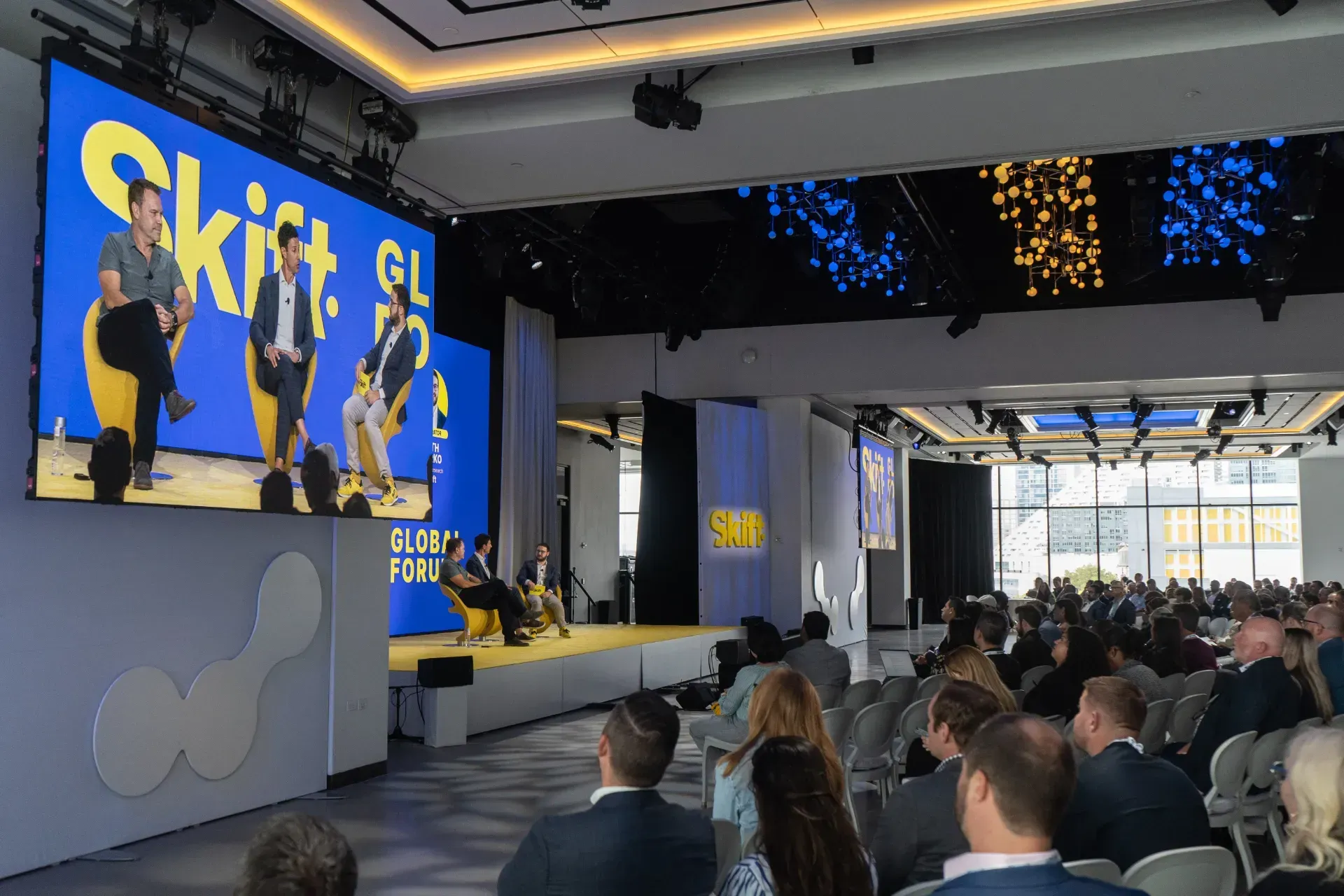 A group of people are sitting in front of a large screen that says shift