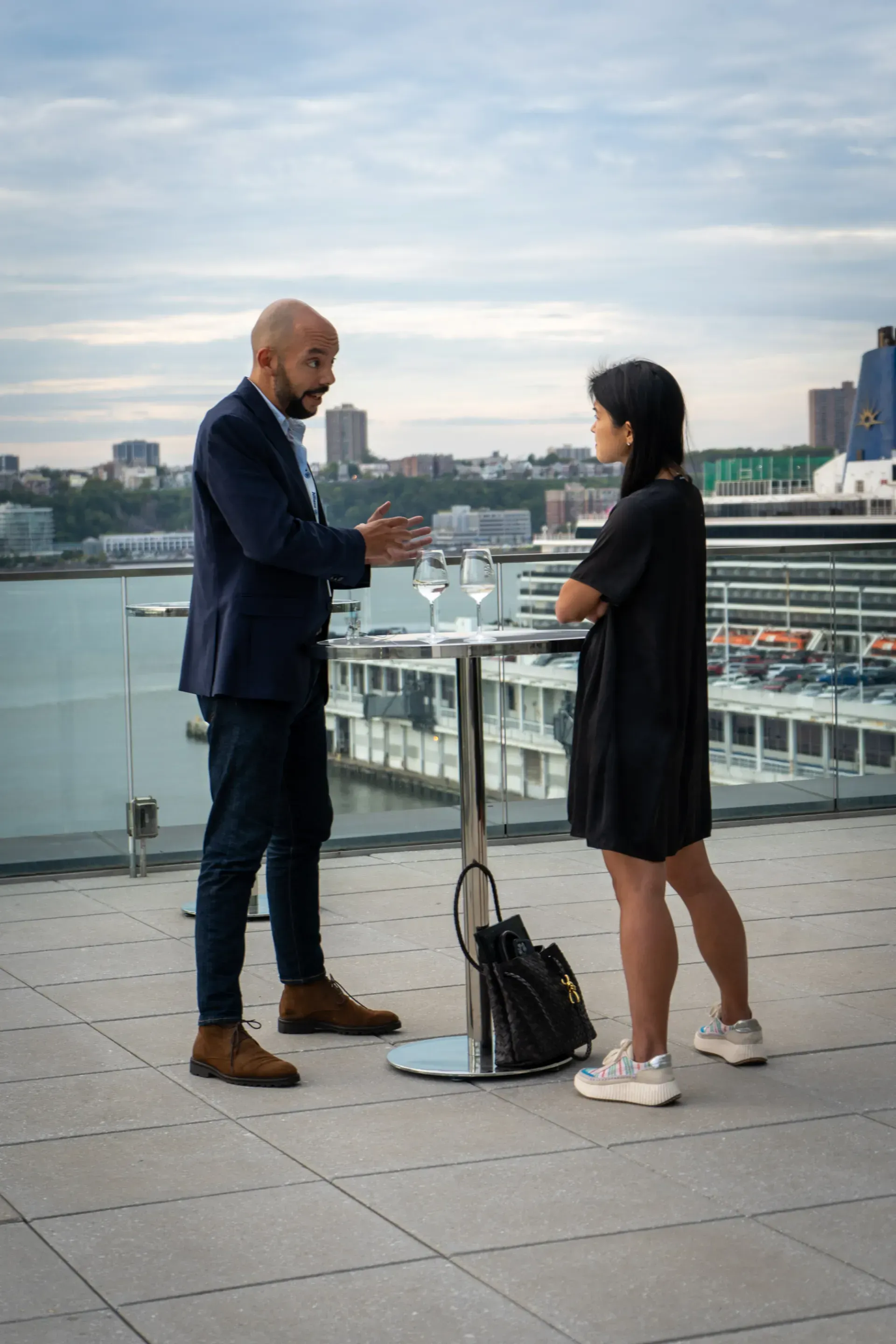 A man and a woman are standing next to a table talking to each other.