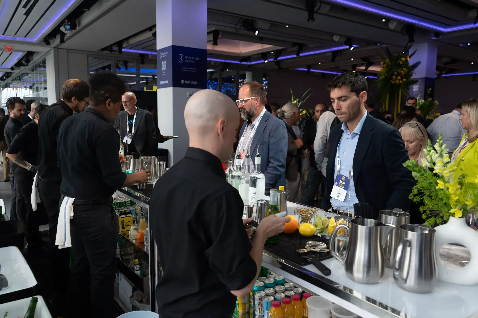 A group of people are standing around a bar.