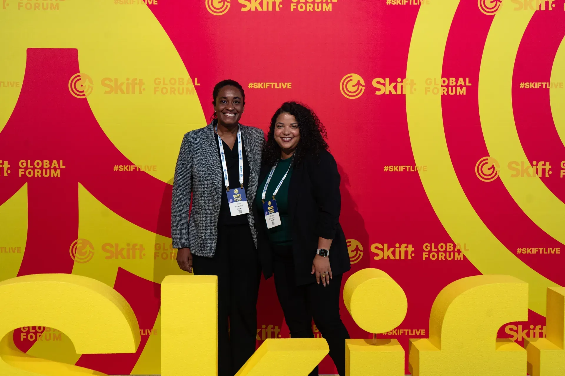 A man and a woman are posing for a picture in front of a yellow wall.