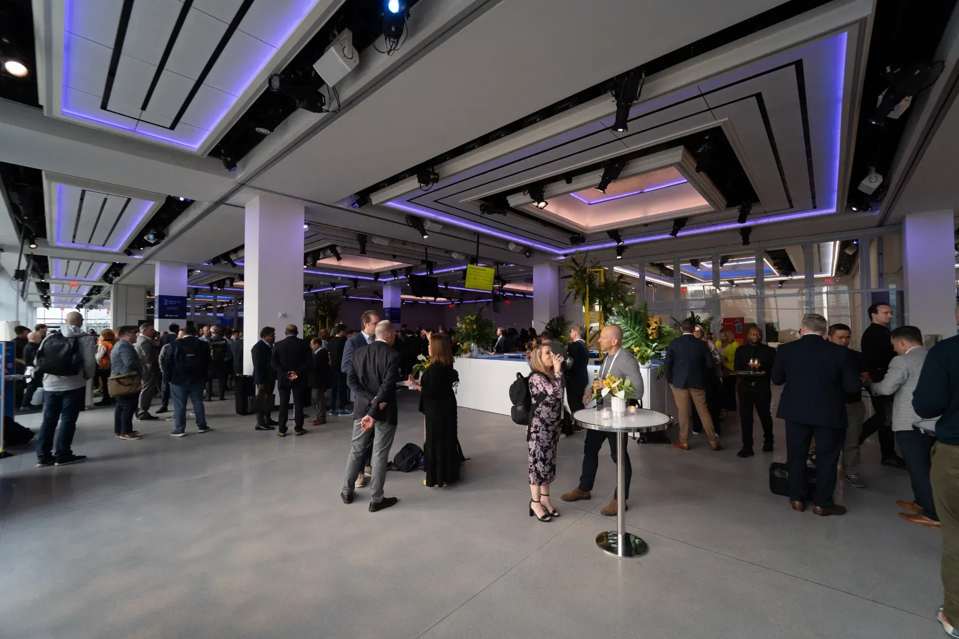 A group of people are standing around tables in a large room.