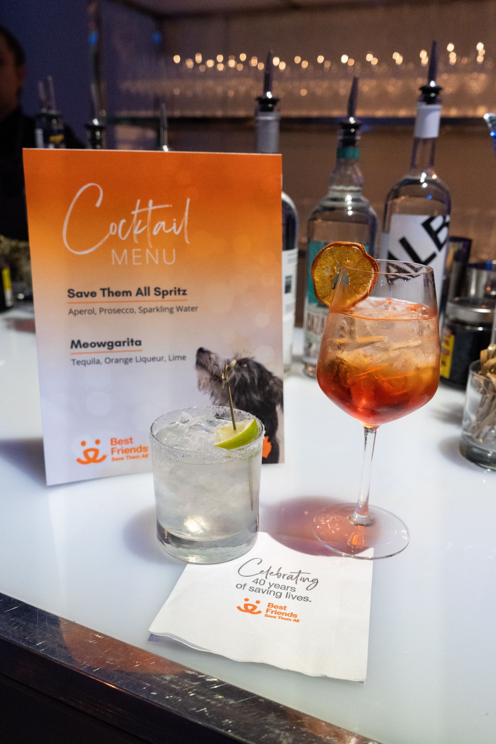 A cocktail menu is displayed next to a glass of cocktail