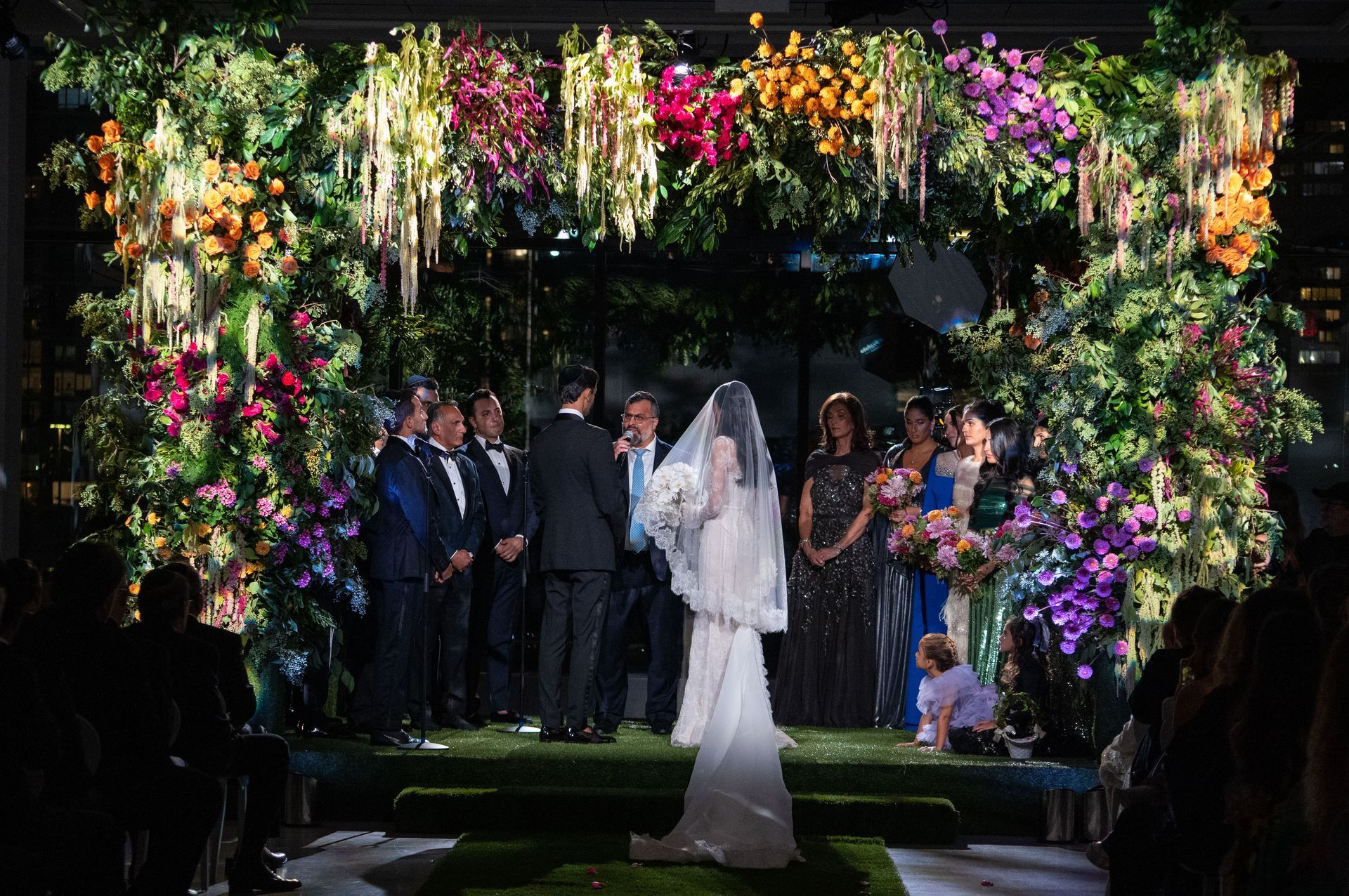 A bride and groom are getting married in front of a wall of flowers.