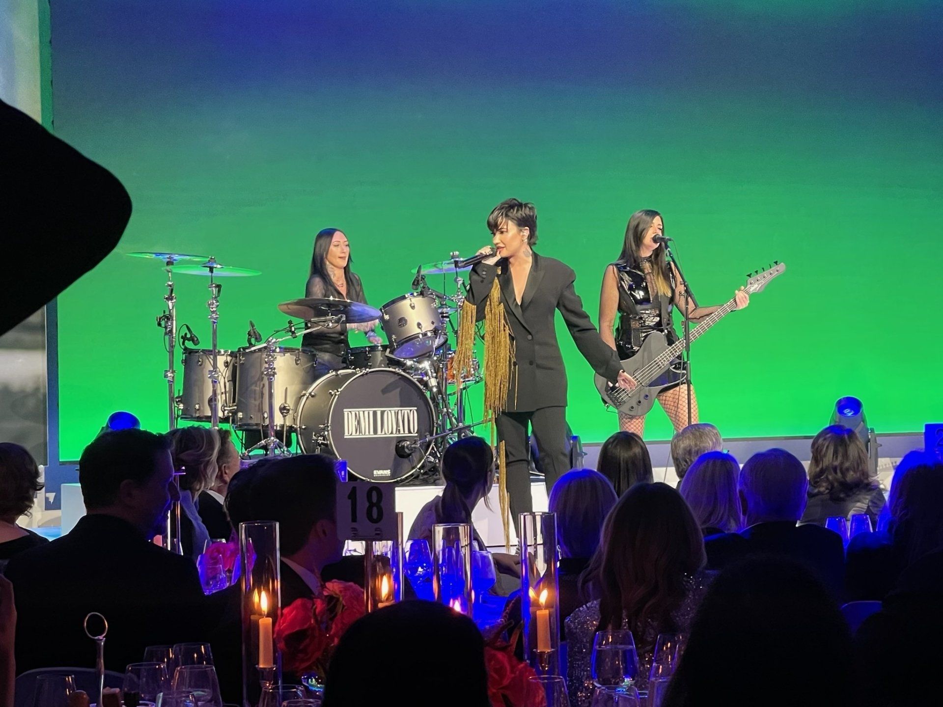 A group of people are sitting at tables watching a band perform on stage.