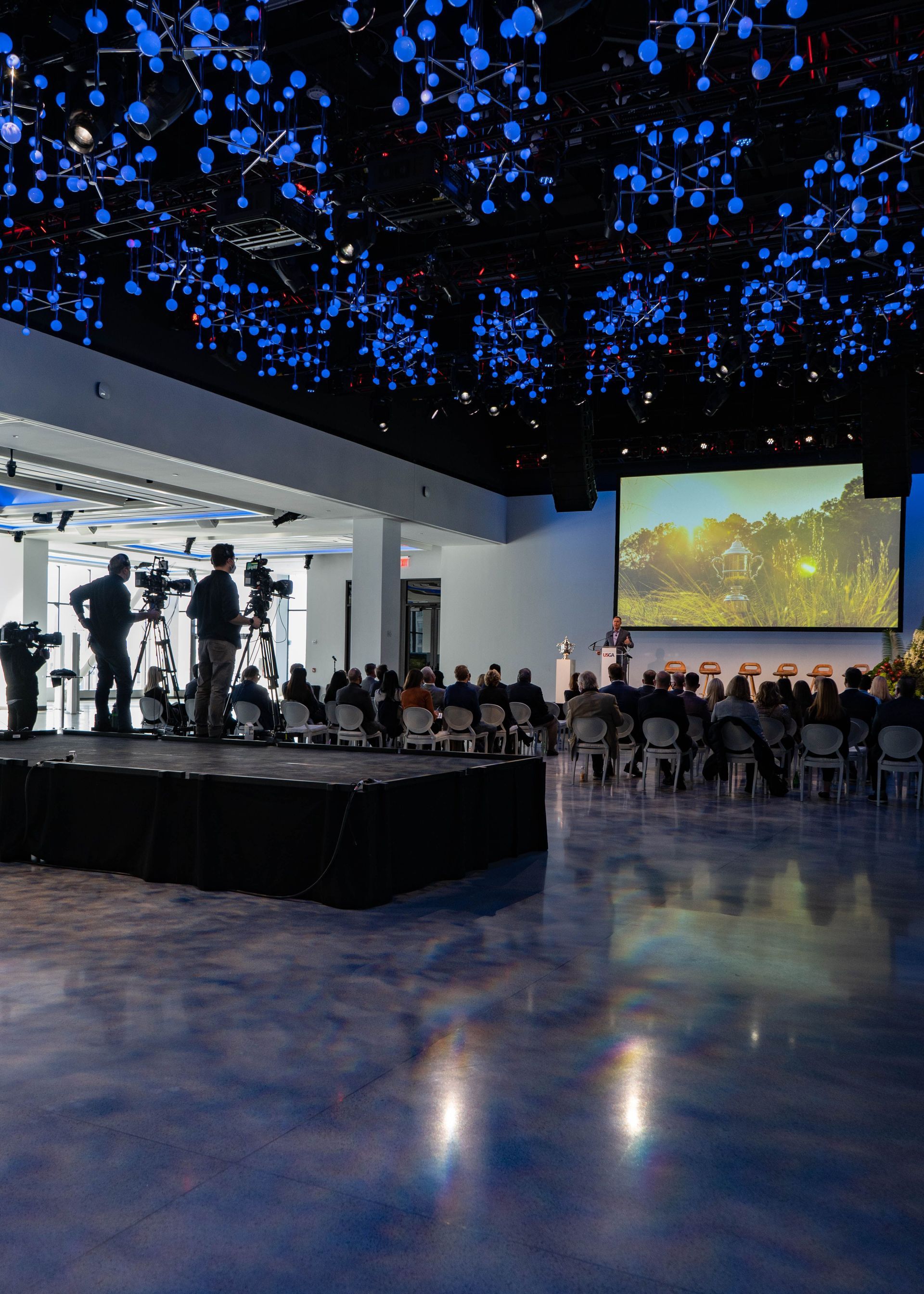 A large room with a circular dance floor and a chandelier hanging from the ceiling.