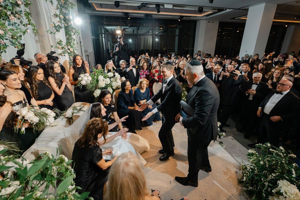 Wedding ceremony with a large crowd; a couple stands under a floral archway.