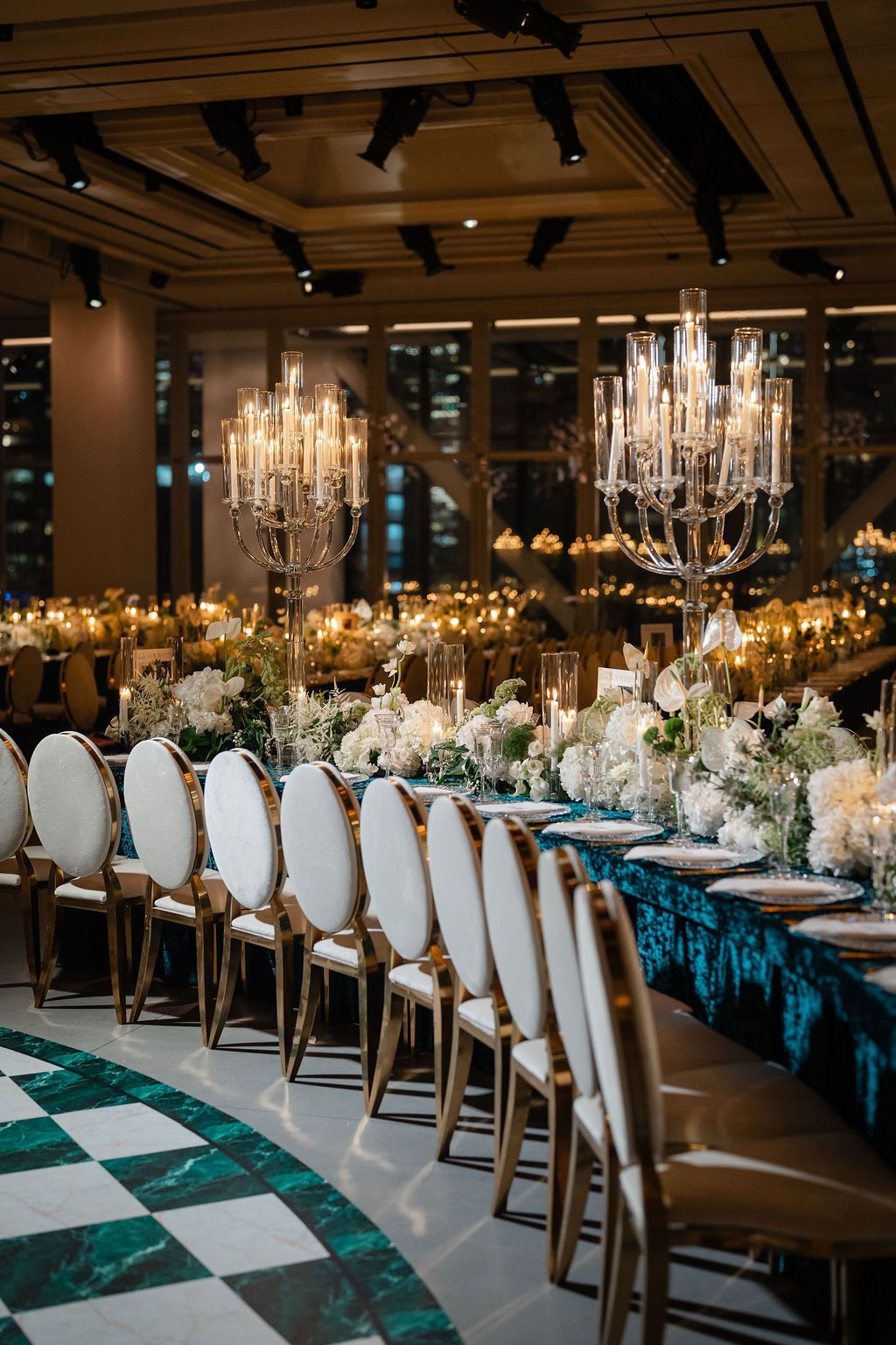 Elegant wedding reception table with gold chairs, teal tablecloth, and floral centerpieces.