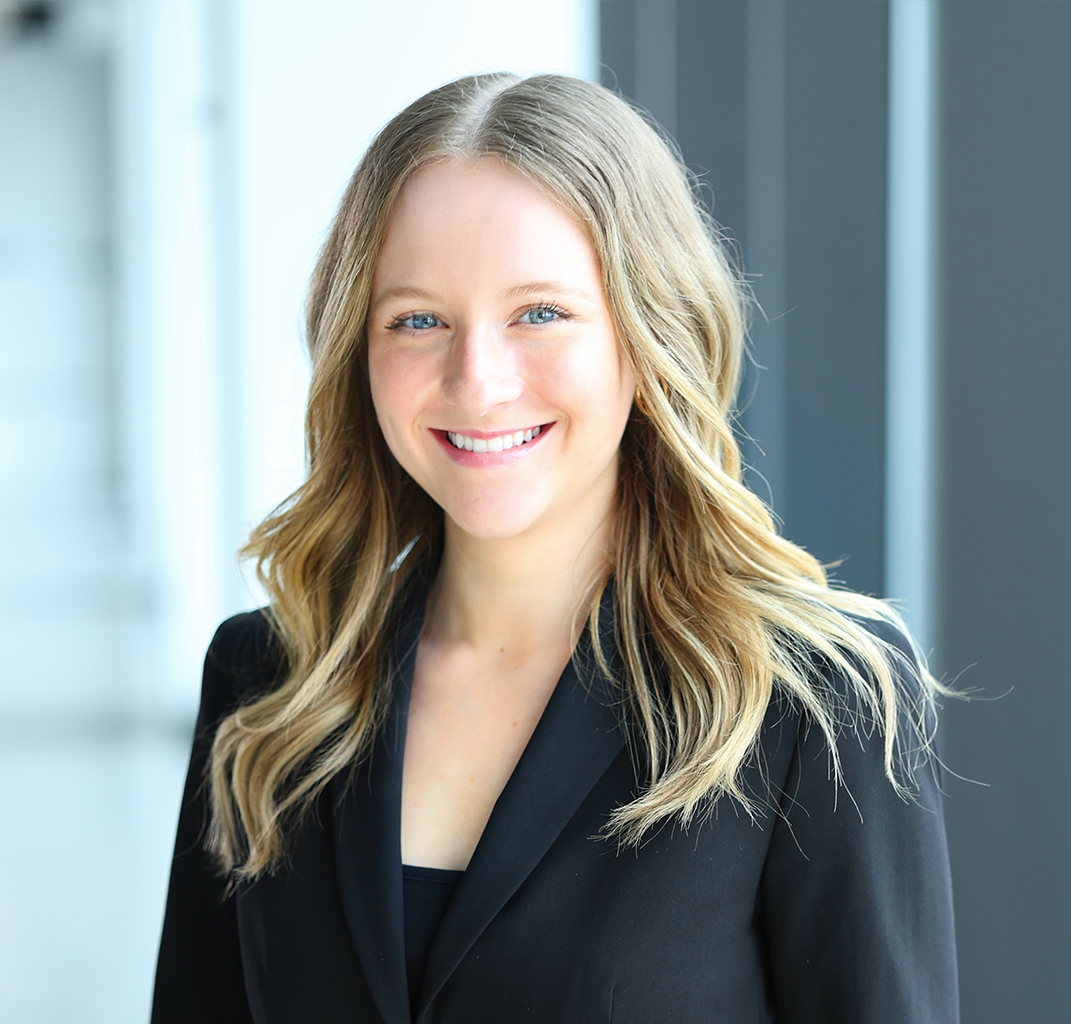 A woman in a black jacket is smiling for the camera.