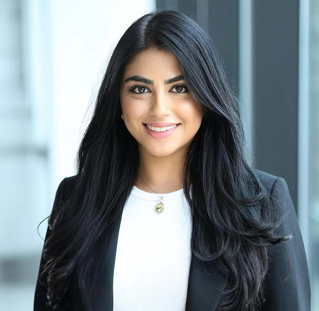 A woman with long black hair is wearing a white shirt and a black jacket.