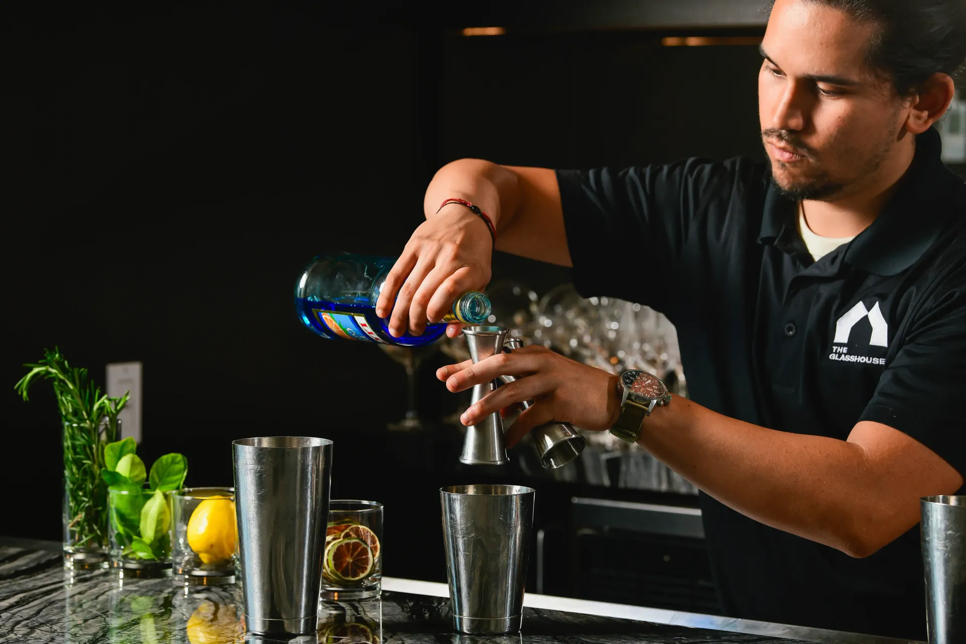 A bartender is preparing a drink with lemon slices and mint leaves.