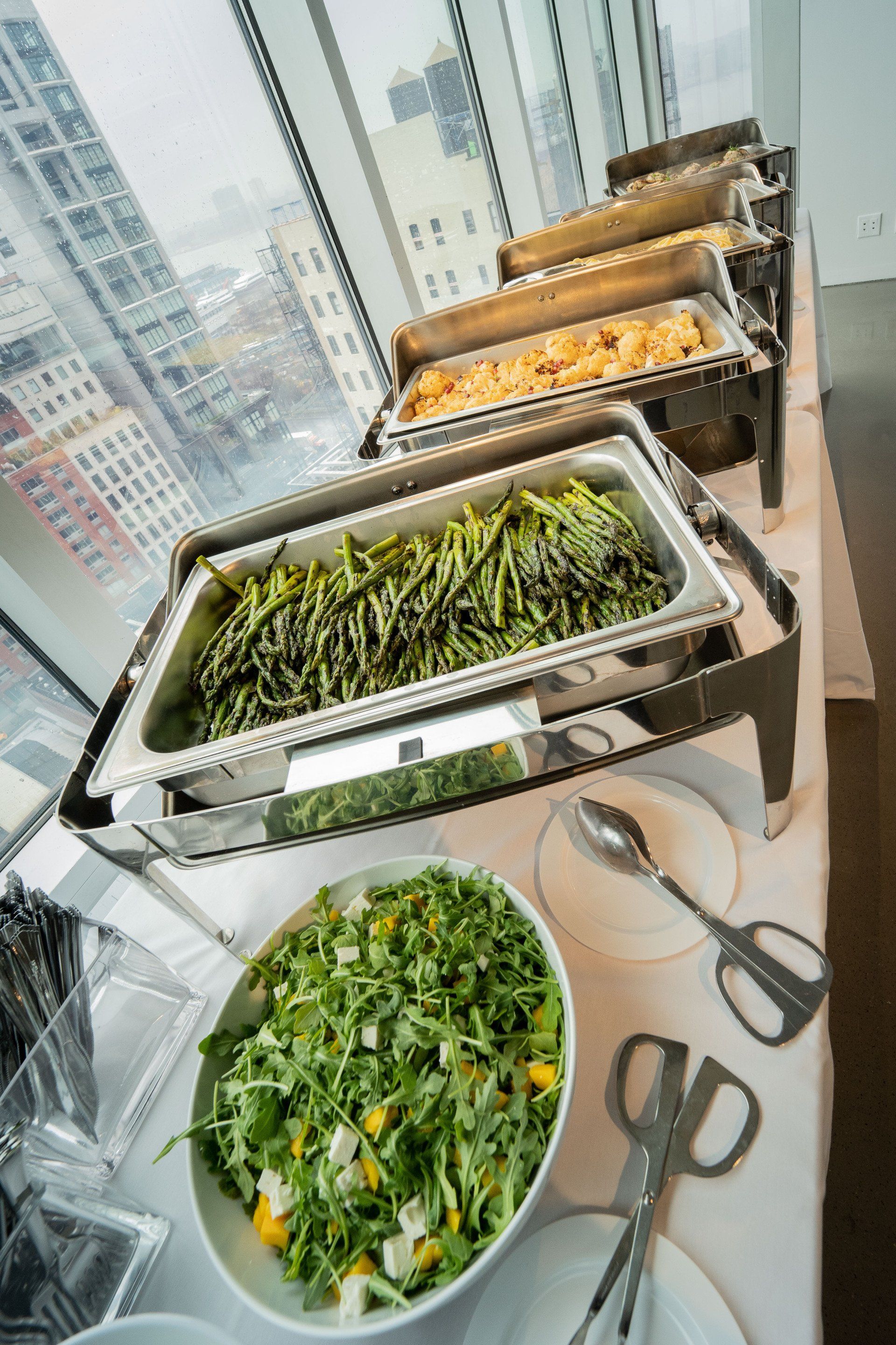 A buffet table with a variety of food and utensils.