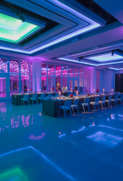 A large room with tables and chairs and purple and blue lights.