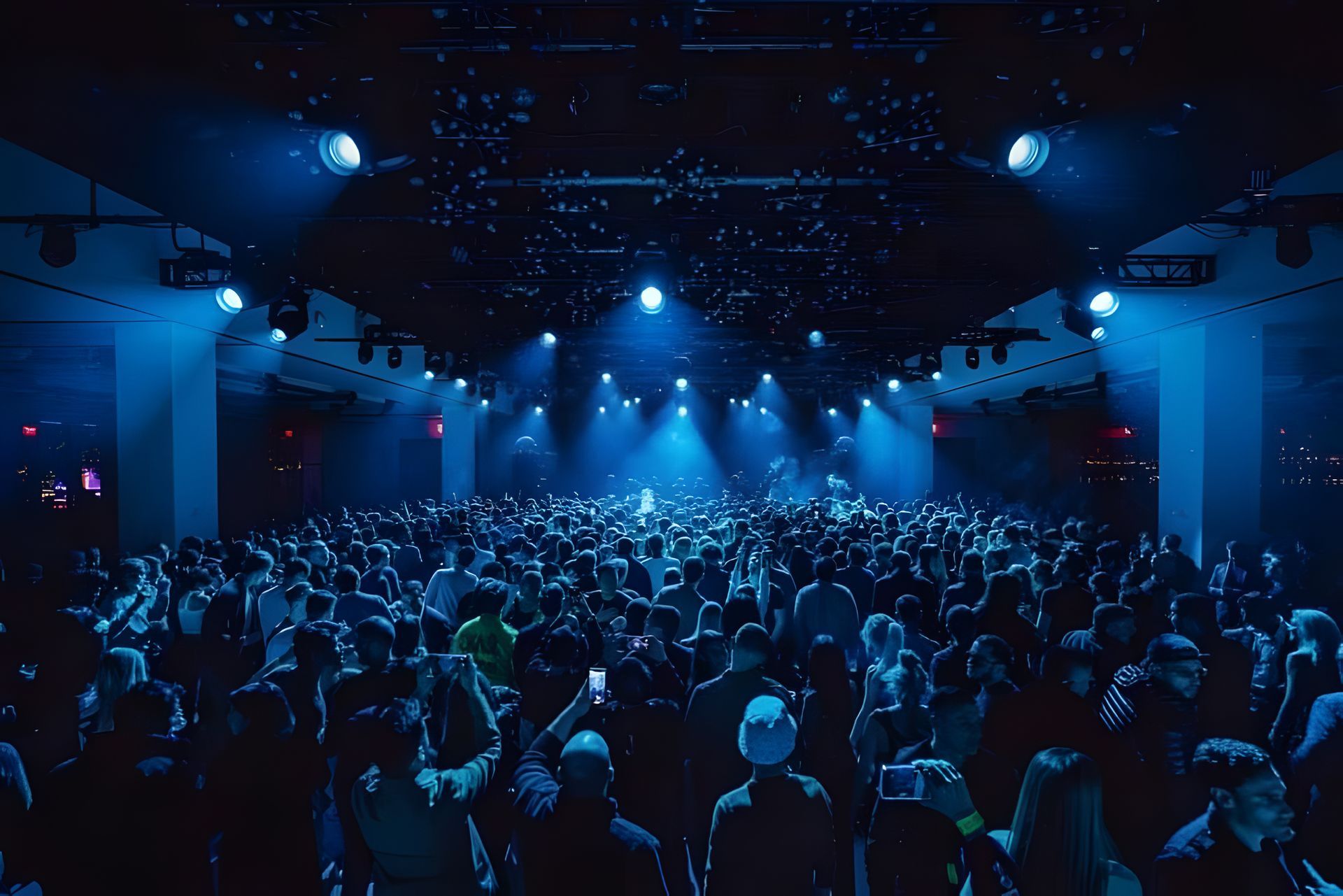 A large crowd of people are standing in front of a stage at a concert.