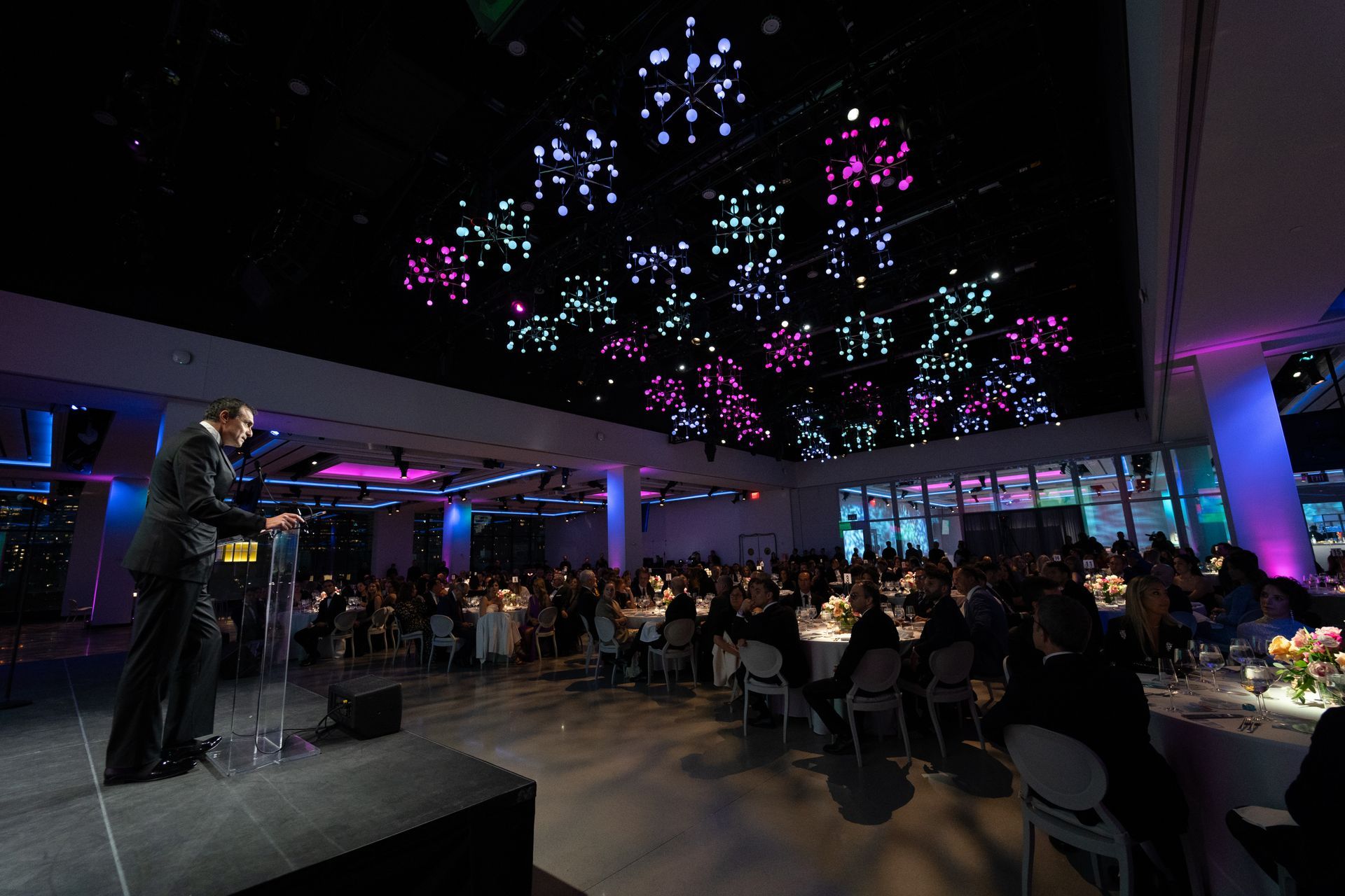 A man is standing on a stage giving a speech in front of a crowd.