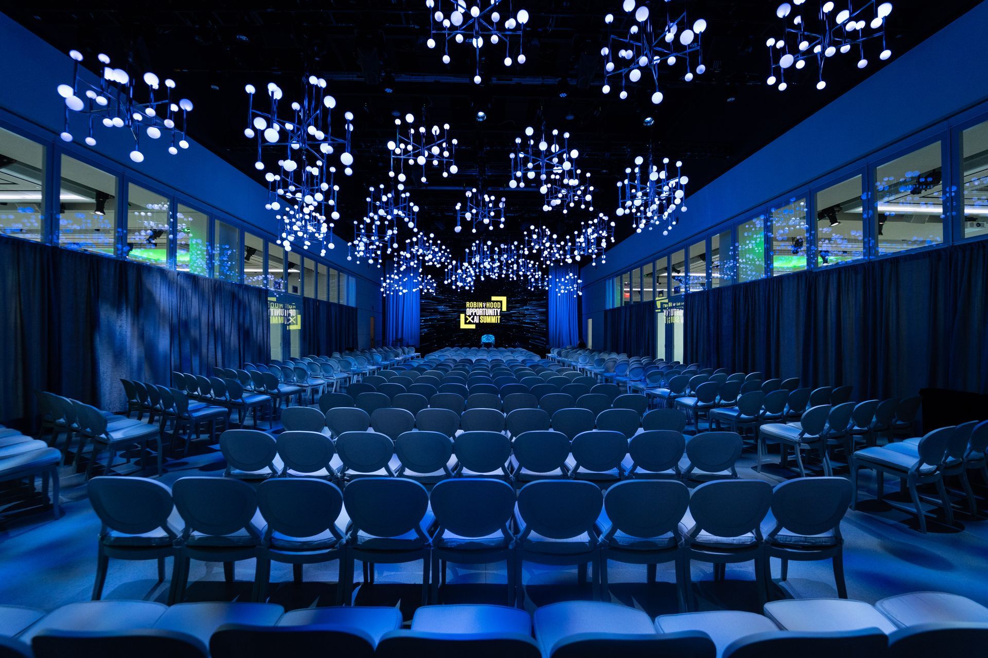 A large auditorium with blue chairs and a stage