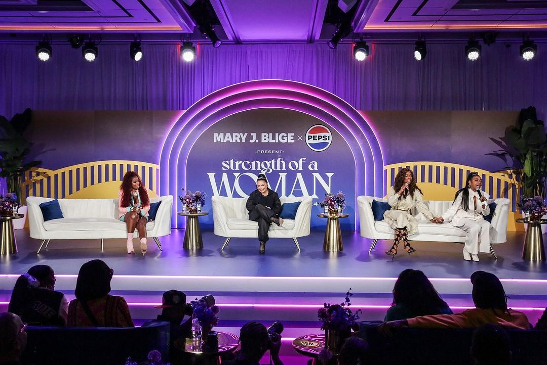 A group of women are sitting on a stage talking to each other.