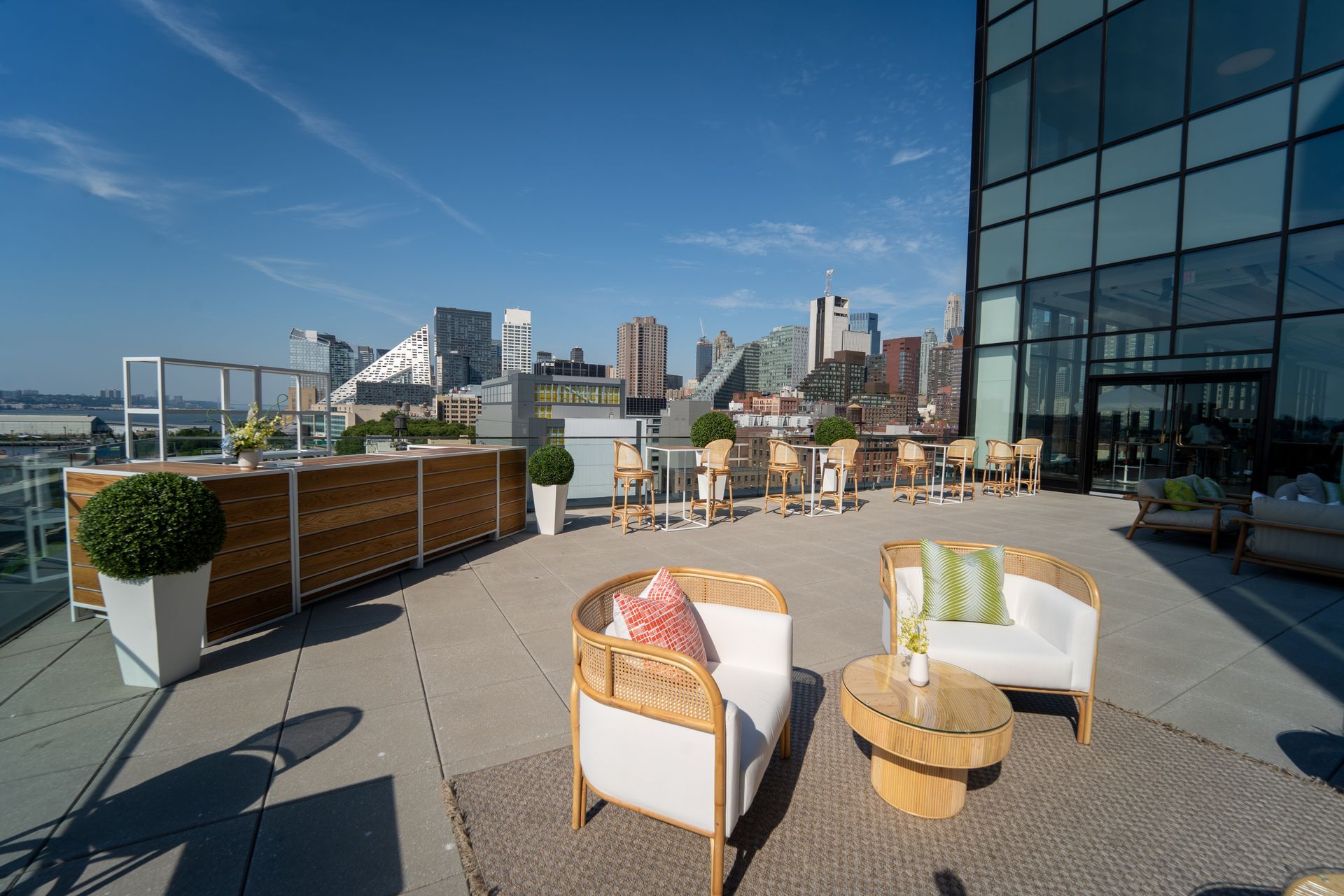 A rooftop patio with chairs , tables and a bar.