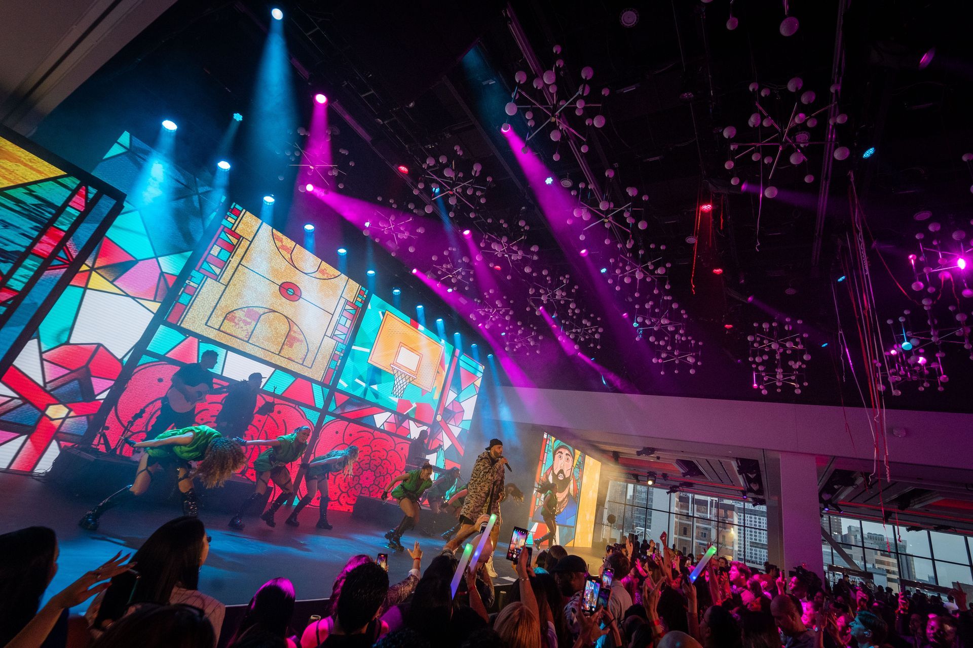A crowd of people are standing in front of a stage at a concert.