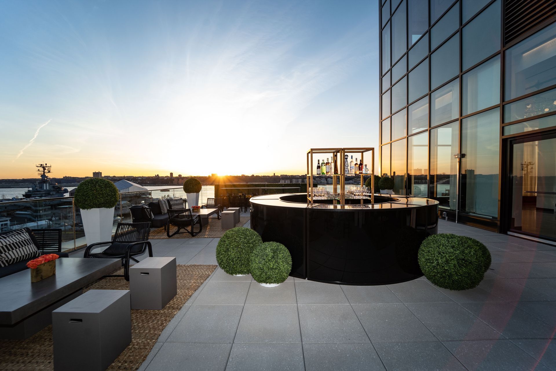 a patio with a bar and a view of the water at sunset