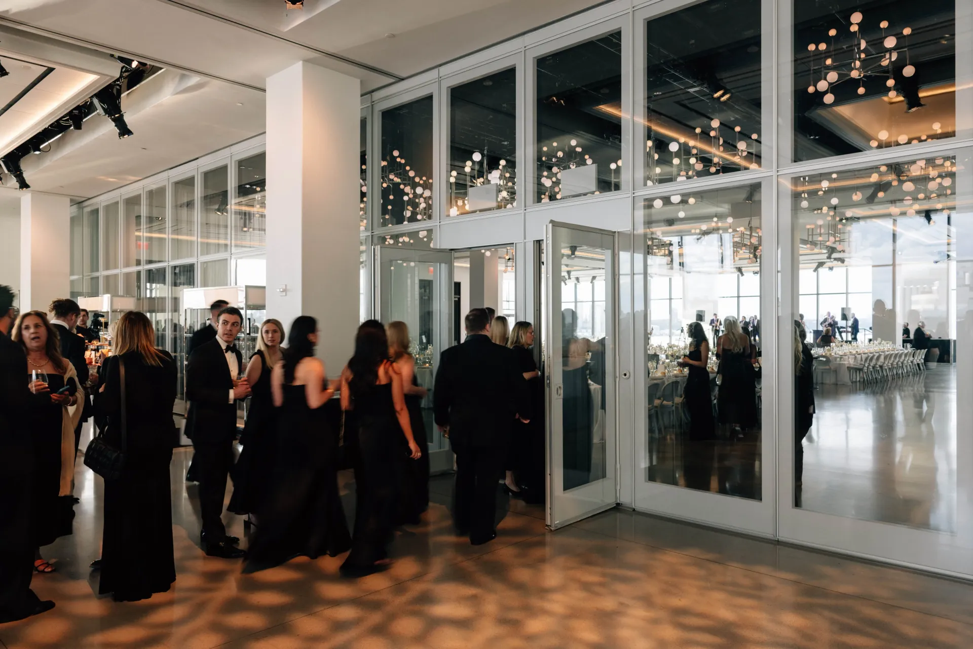 A group of people are standing in a room with a lot of windows.