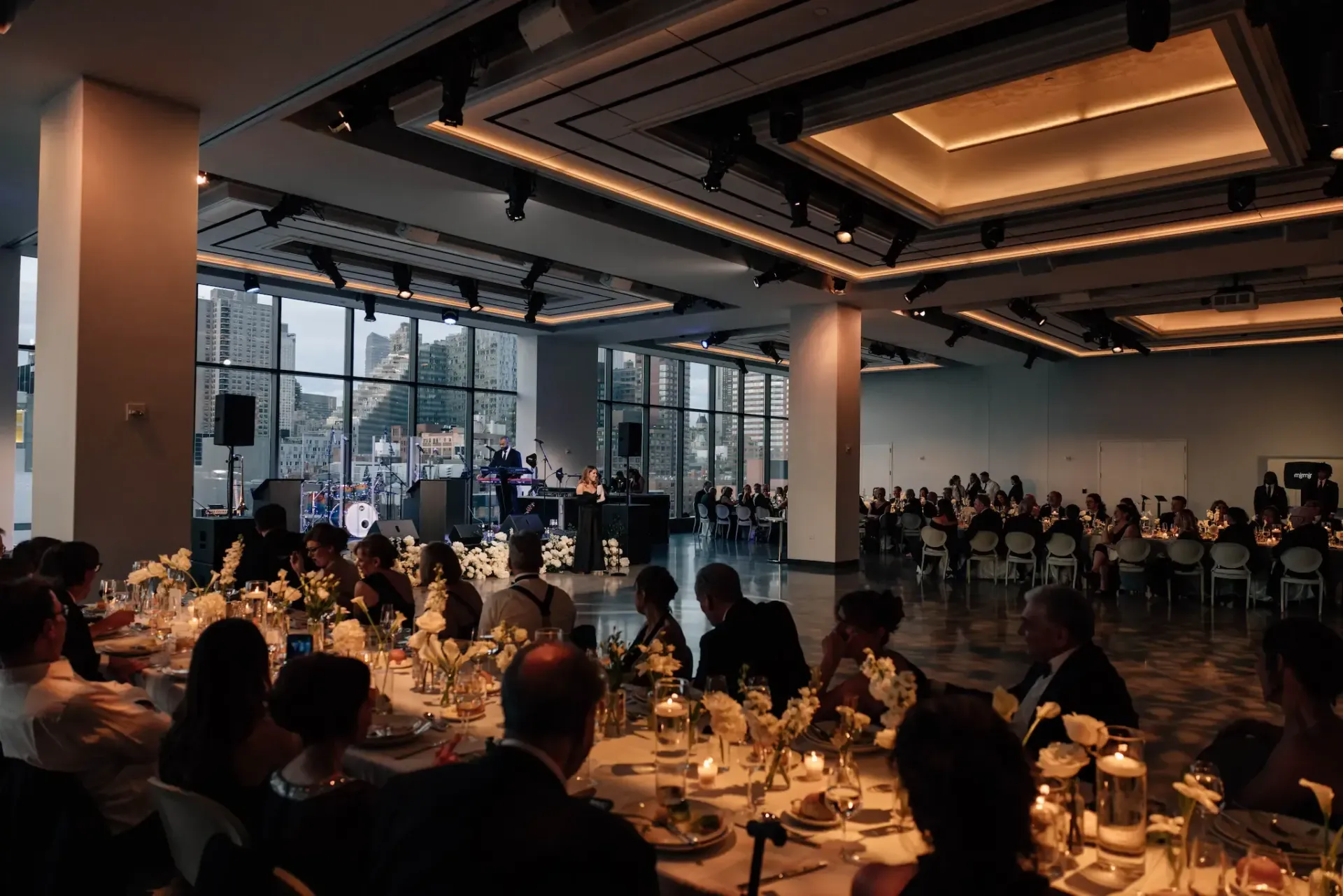 A large room filled with people sitting at tables.