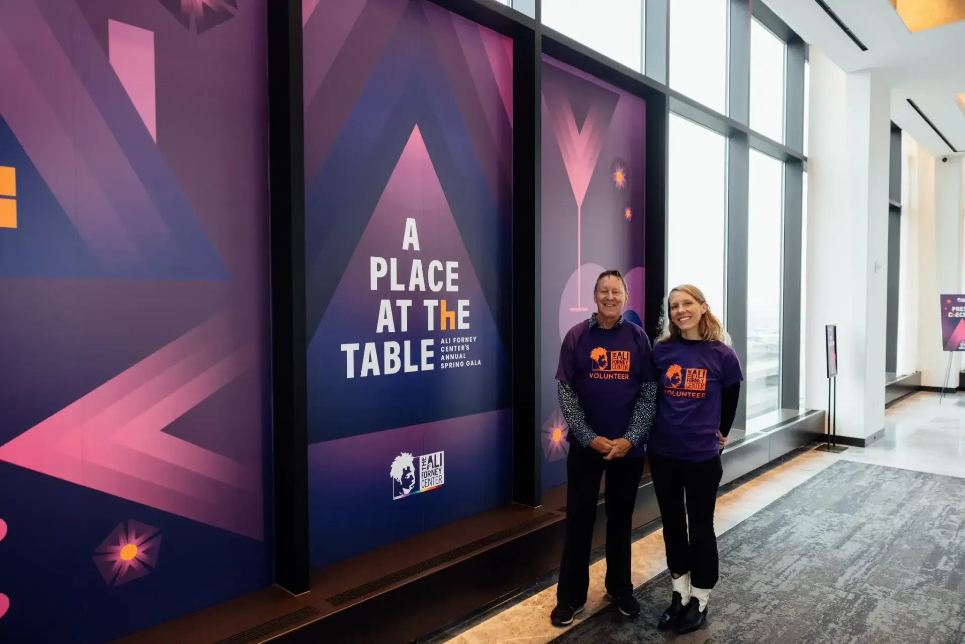 A man and a woman are standing in front of a sign that says `` a place at the table ''.