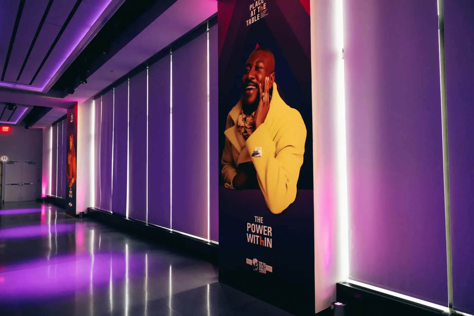 A long hallway with purple lights and a painting of a man on the wall.