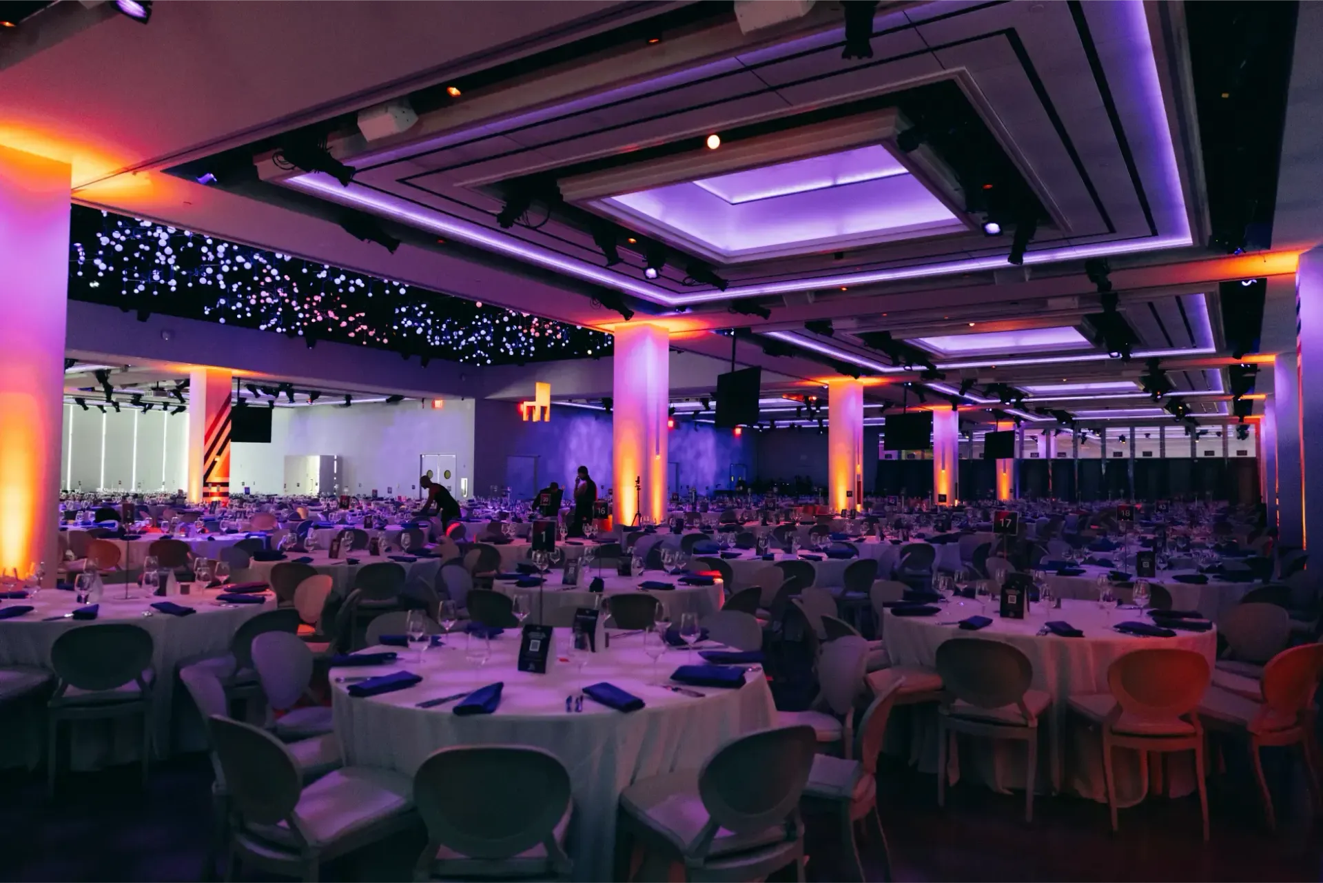 A large room filled with tables and chairs and purple lights.