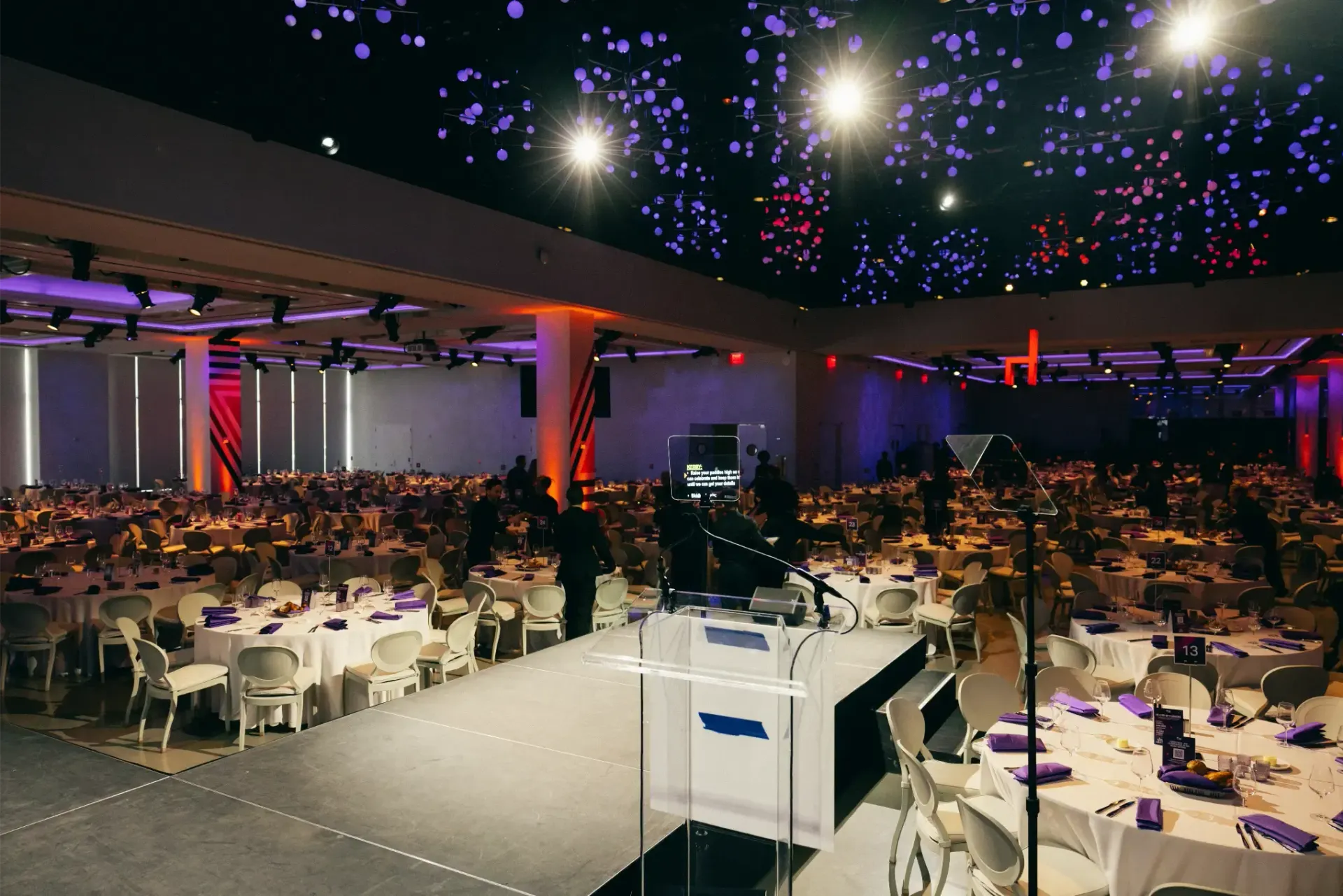 A large room with tables and chairs and a podium in the middle.