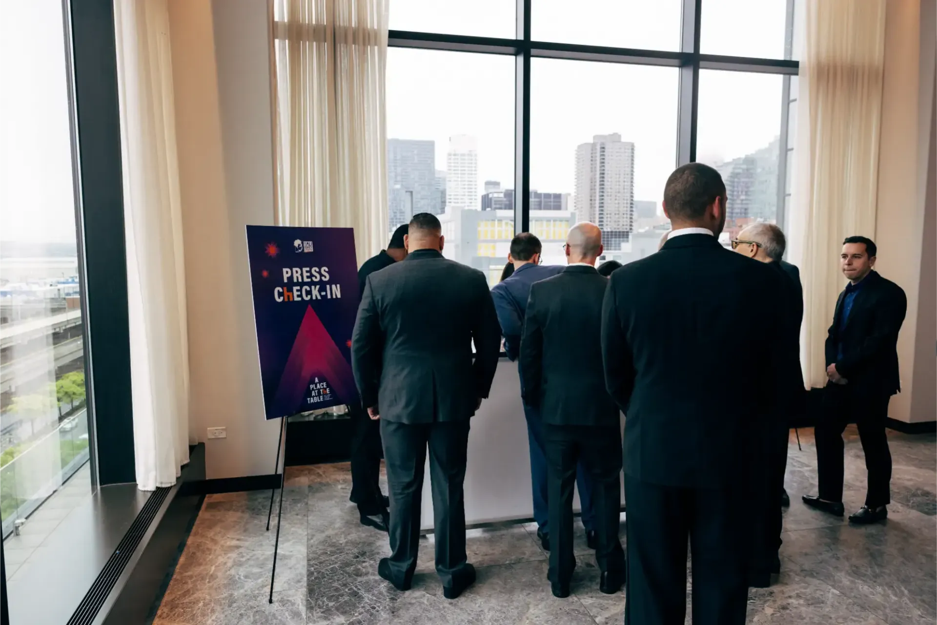 A group of men in suits are standing in front of a large window.