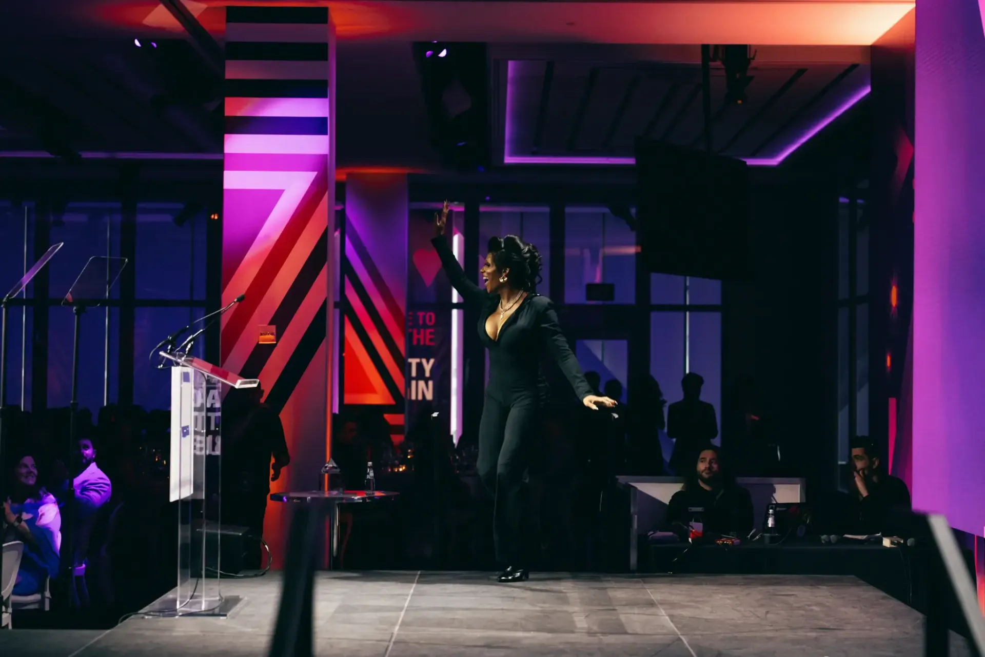 A woman is dancing on a stage in a dark room.