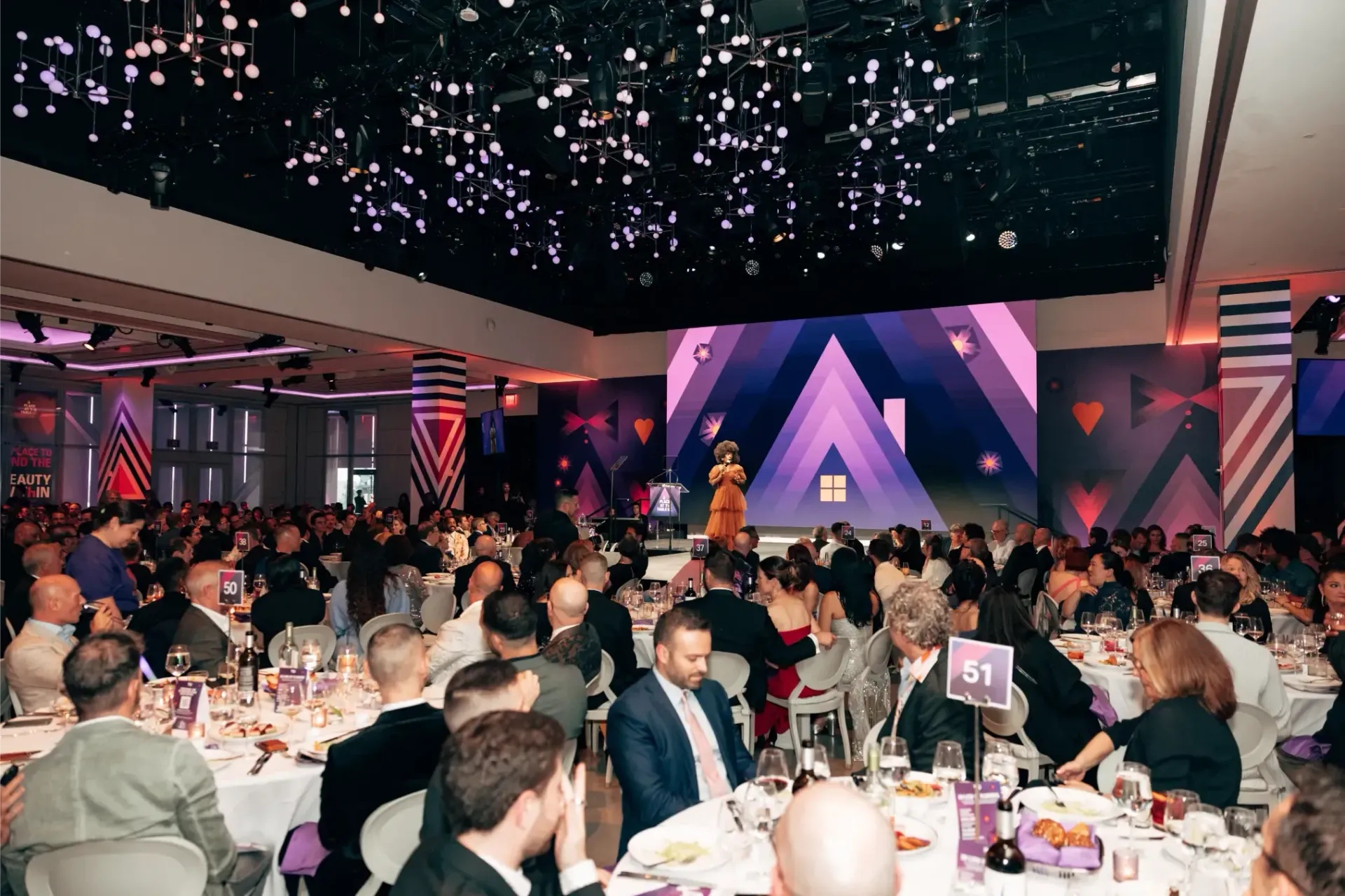 A large group of people are sitting at tables in a large room.