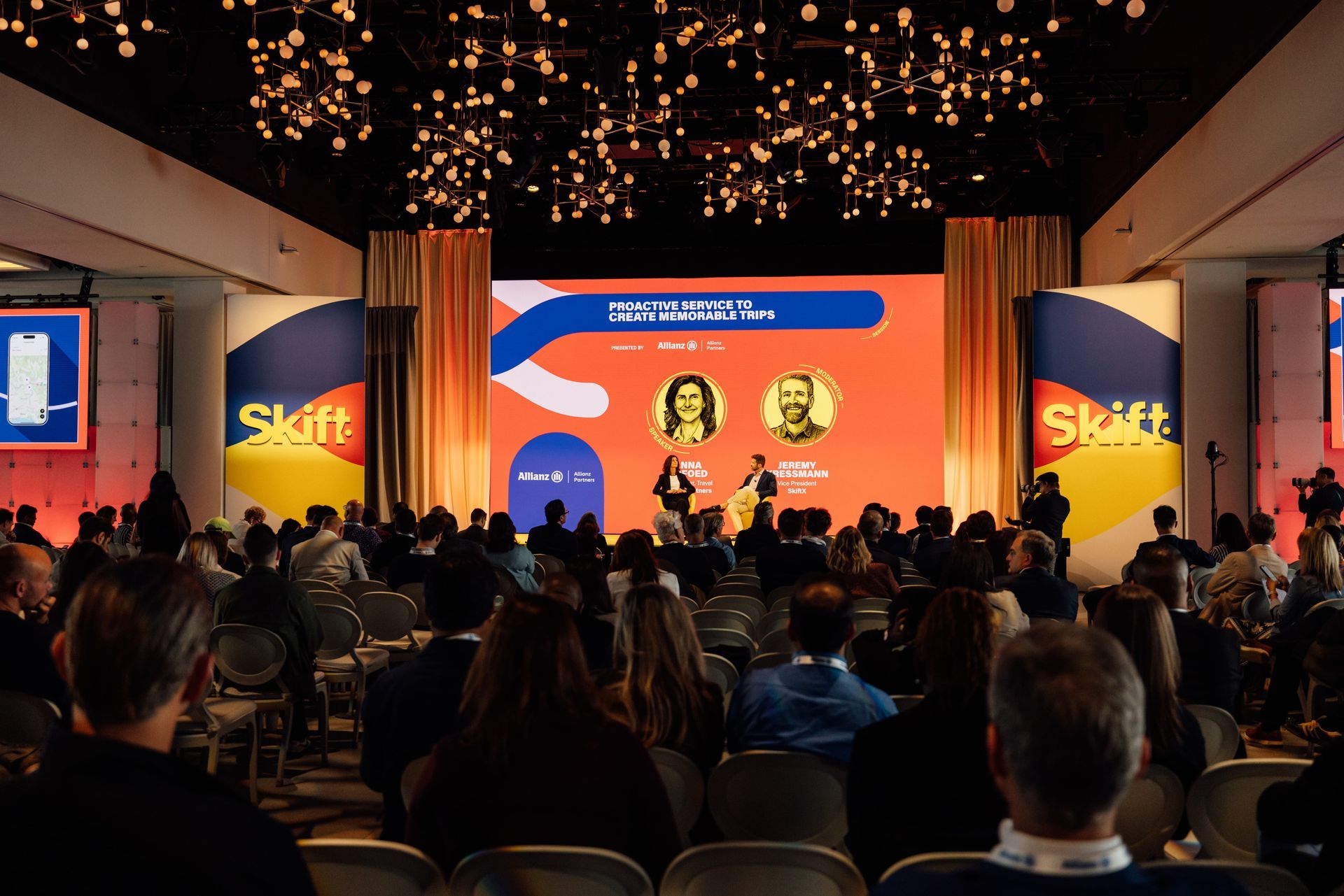 Conference stage with speakers, audience, and Skift branding in a large room.