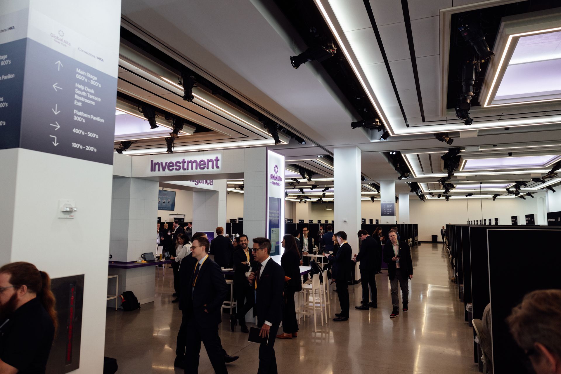 People in suits at an investment event, with signs for 