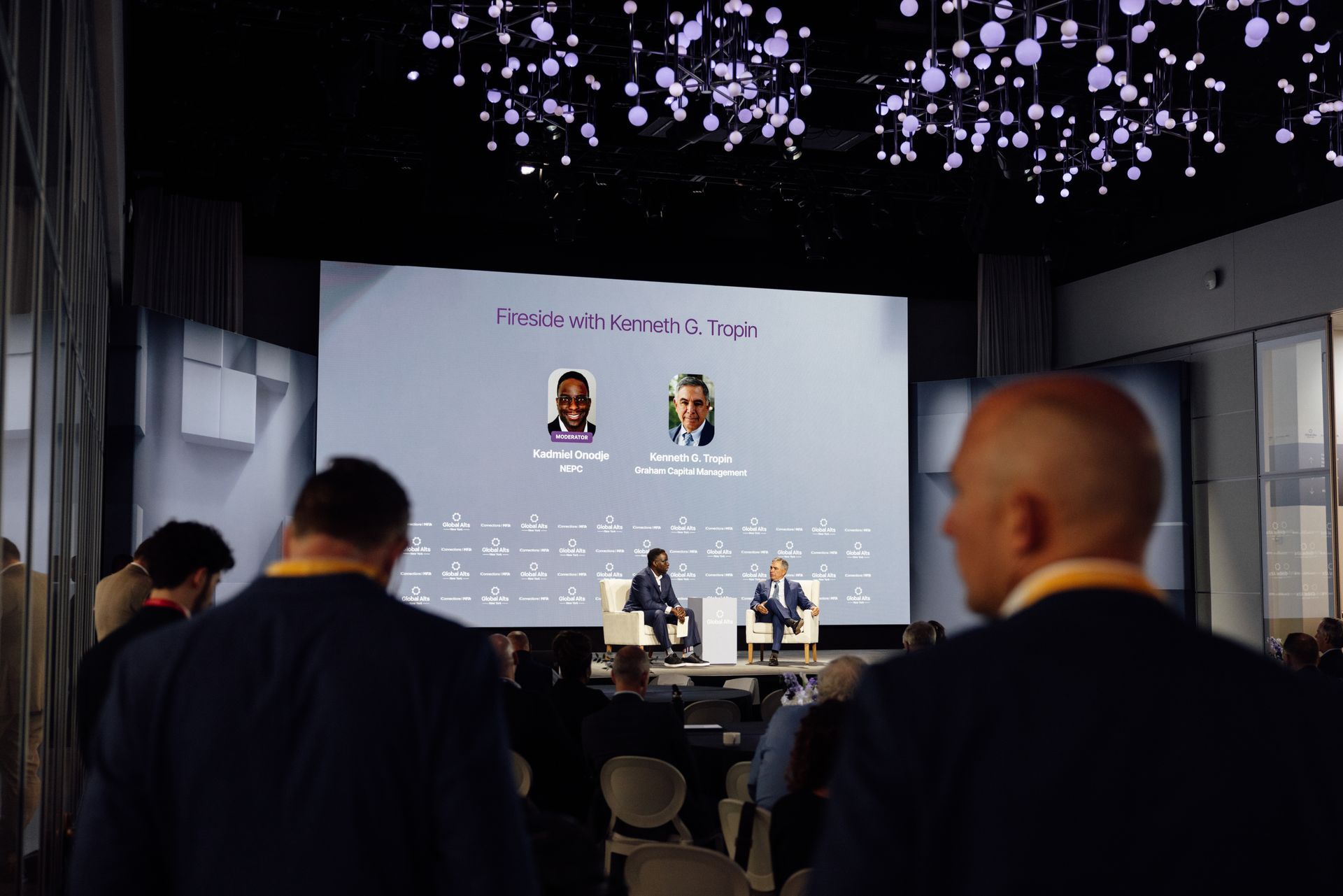 Panel discussion on stage with two speakers; audience in foreground.